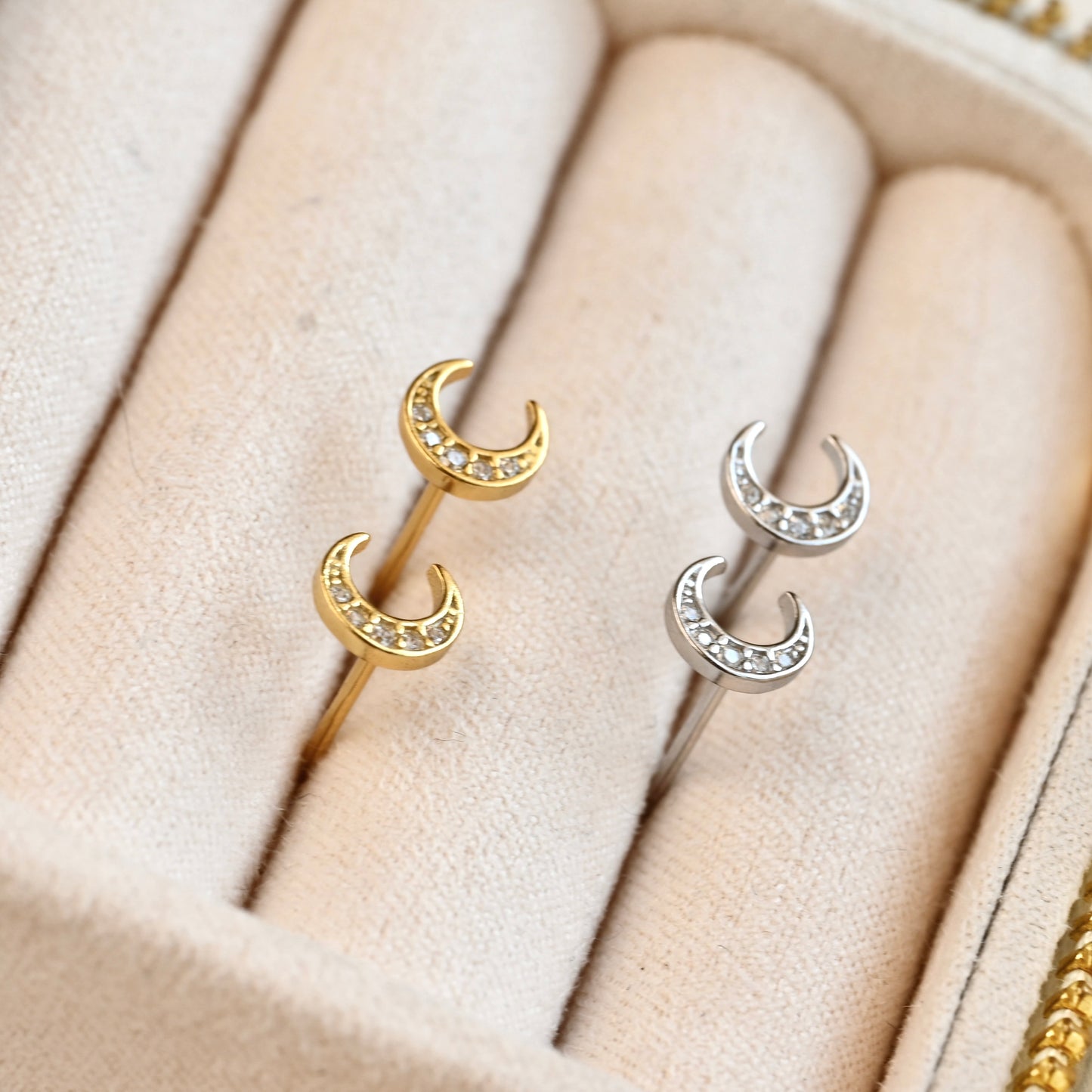 Pair of gold and silver celestial earrings on a soft beige fabric background