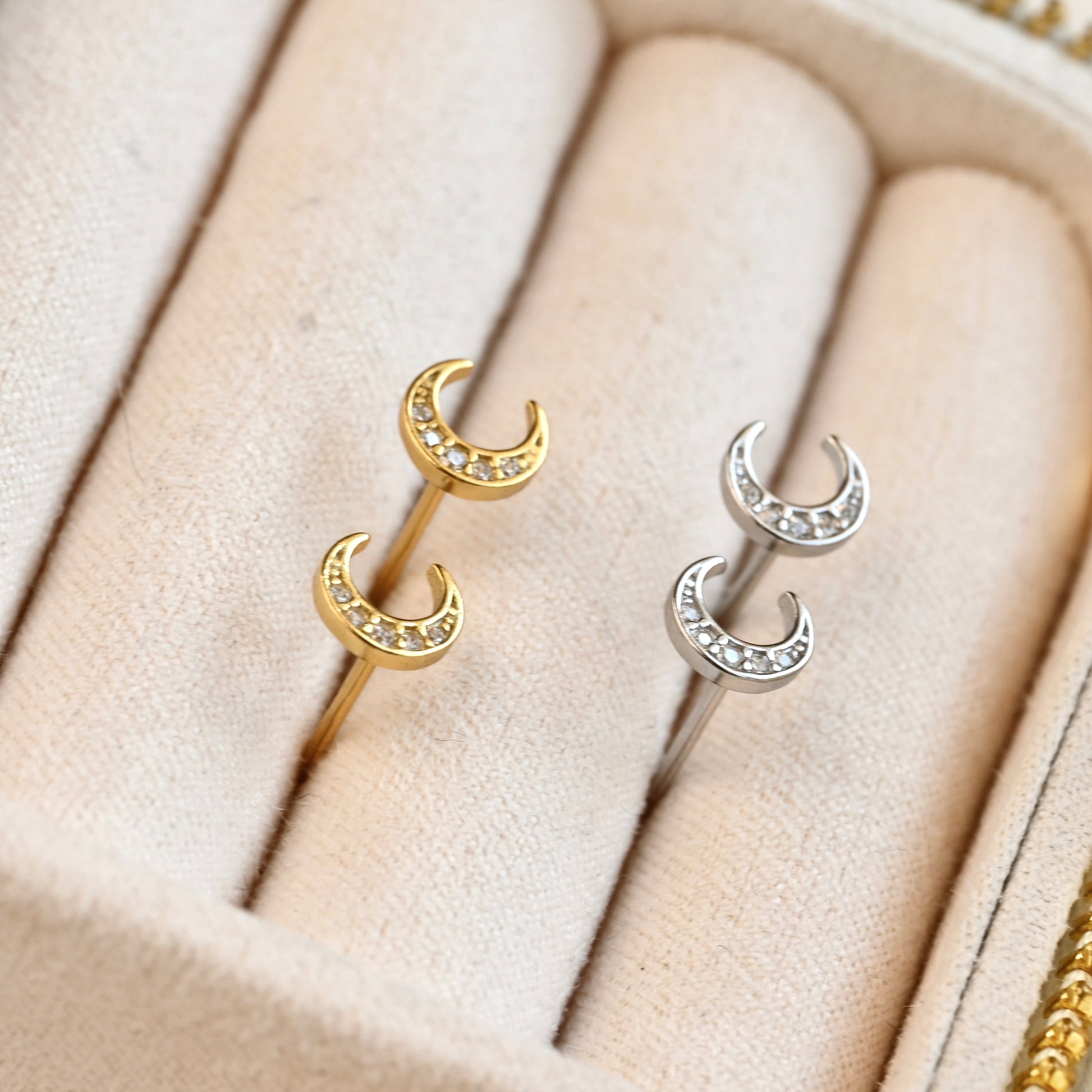 Pair of gold and silver celestial earrings on a soft beige fabric background