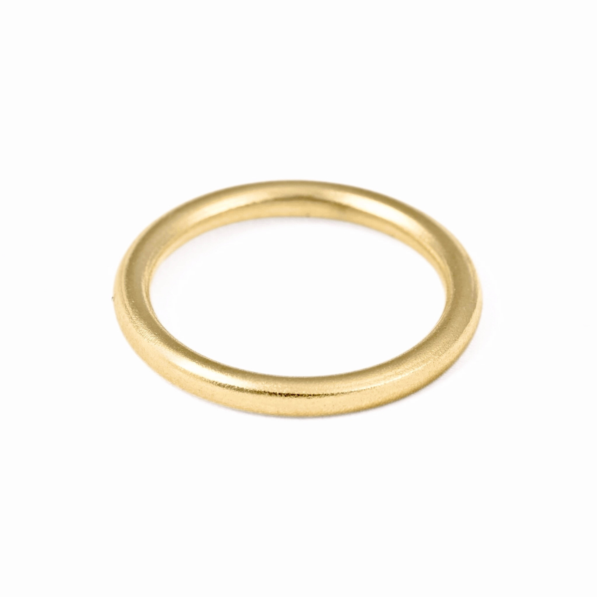 Thin gold band with grainy satin finish on white surface.
