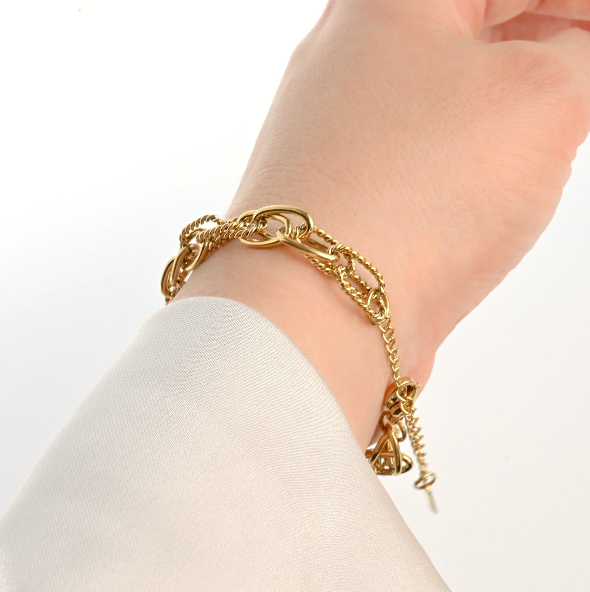 Gold  layered link chain bracelet with a with a cable extender chain on a wrist against a white background