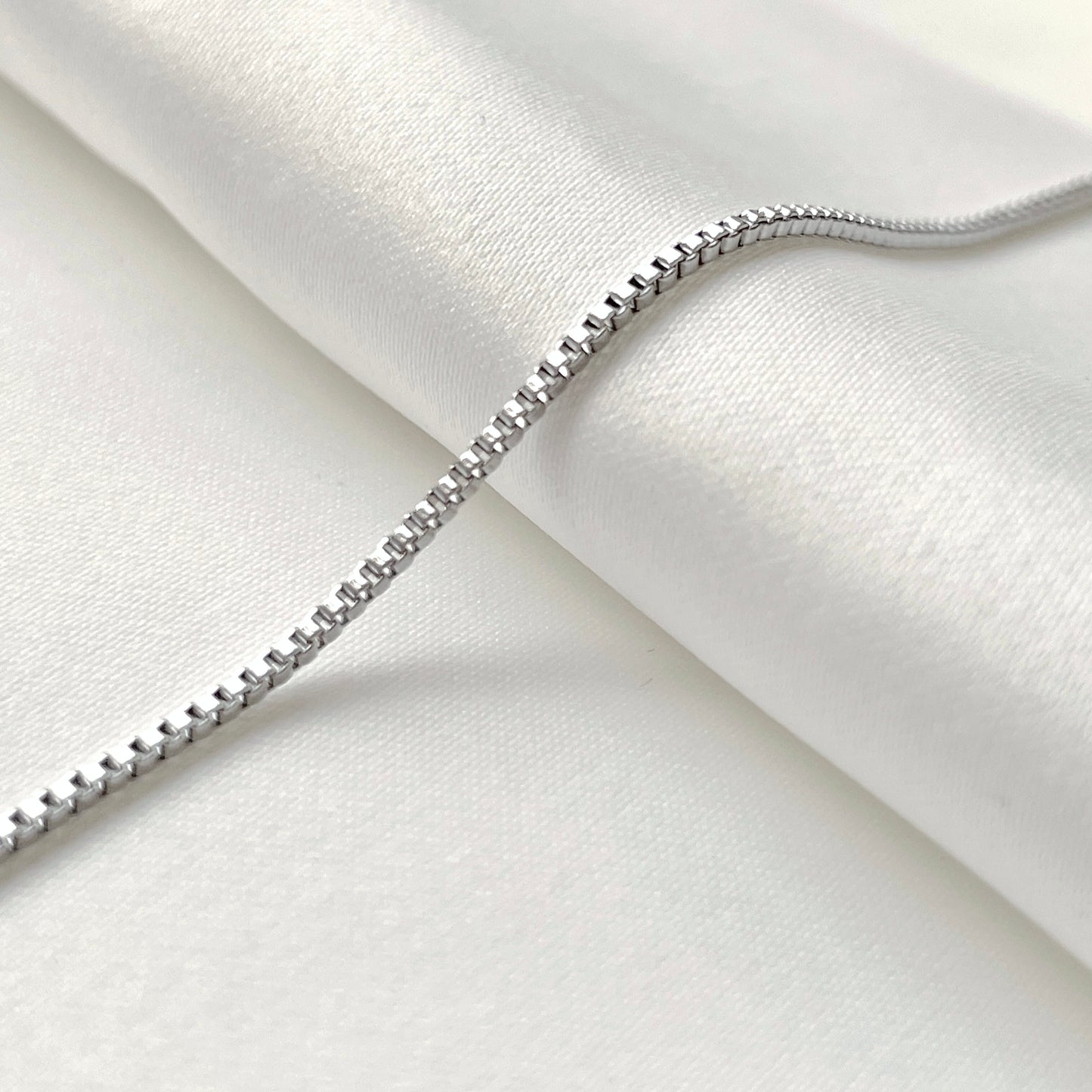 Delicate silver chain bracelet on a white fabric background