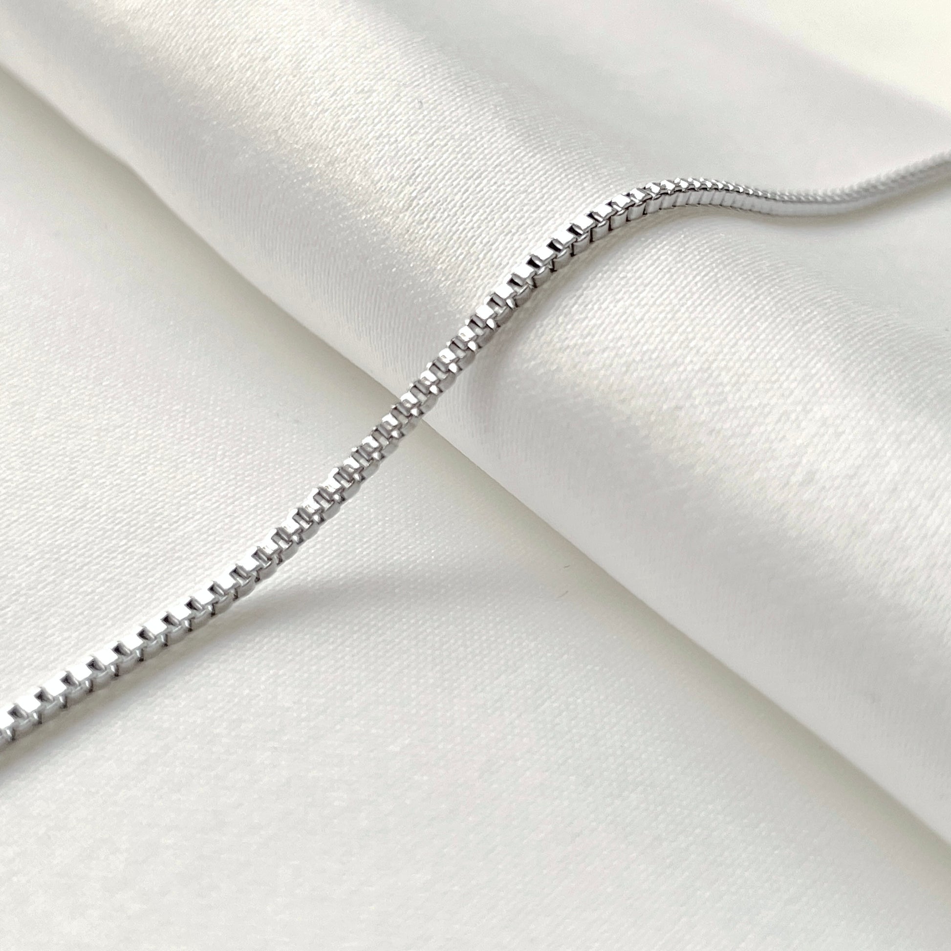 Delicate silver chain bracelet on a white fabric background