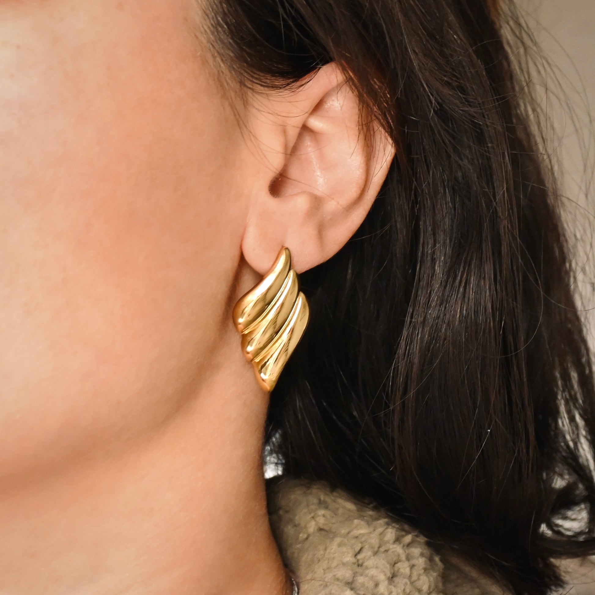 Large Gold rhombus earrings worn by a person with dark hair.