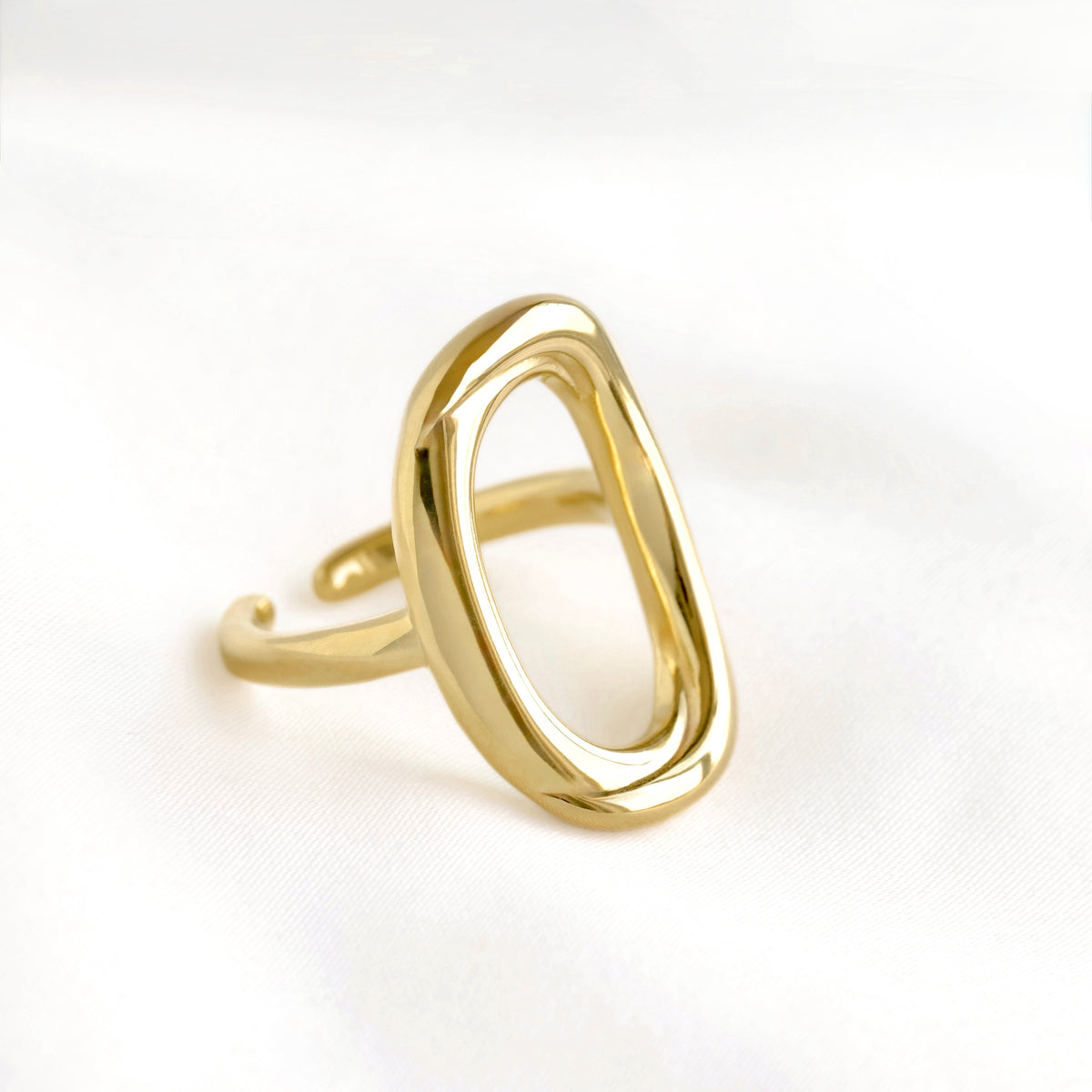 Close-up view of an open oval rounded statement rin g in 14k gold color and with an open back on white background.