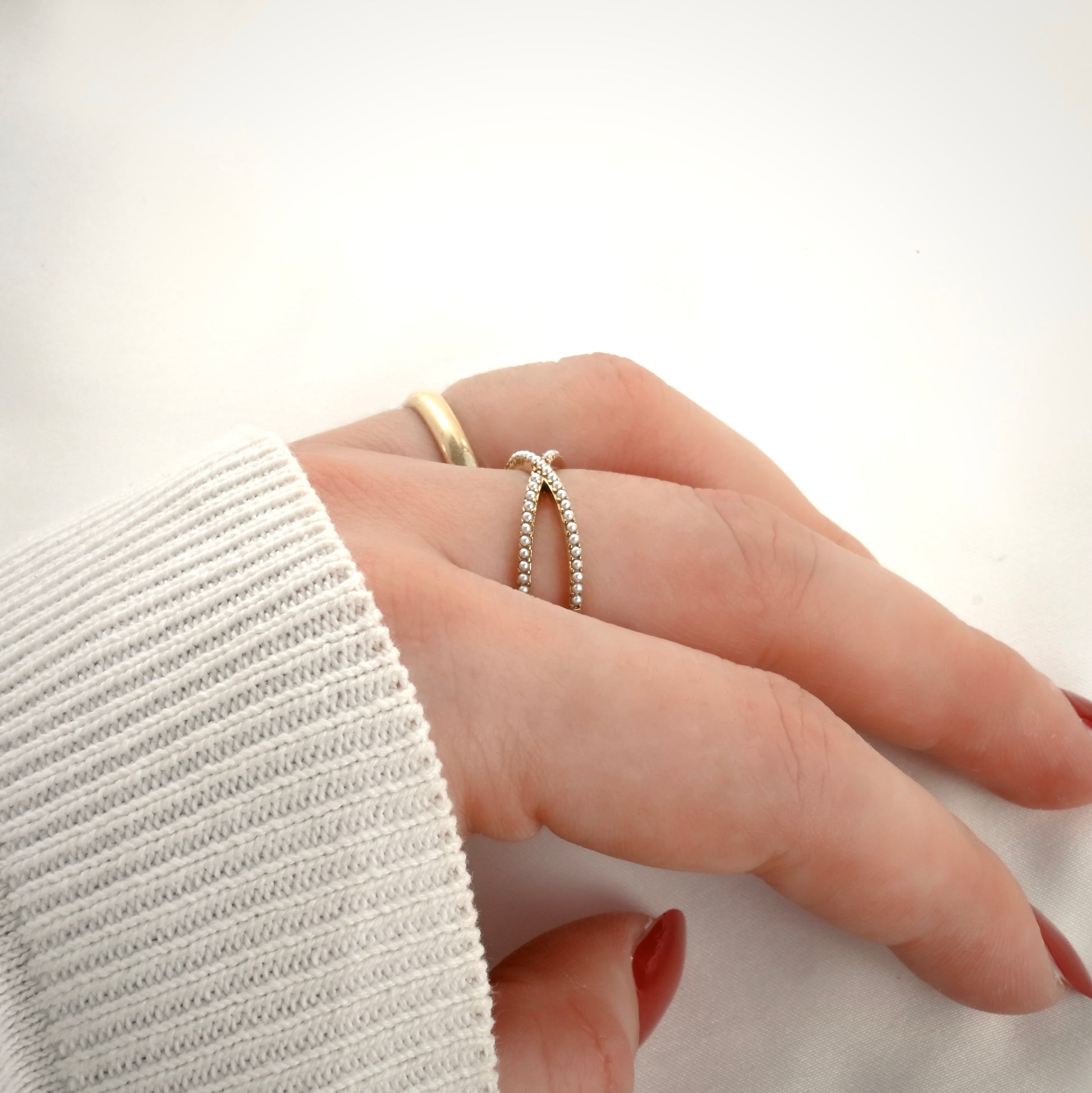 Close-up side view of a hand wearing two rings on a white background