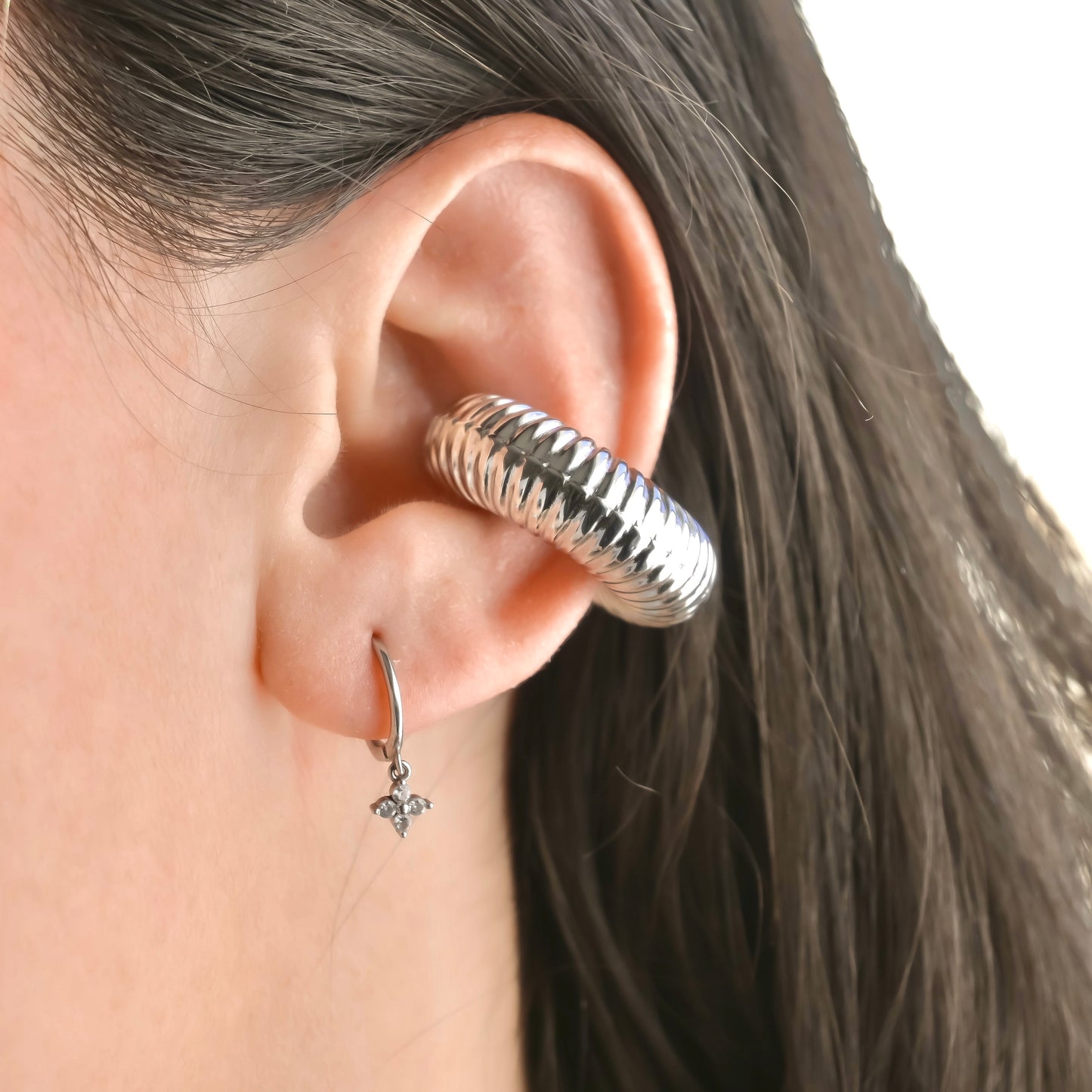 Close-up of an ear wearing a ribbed silver cuff earring