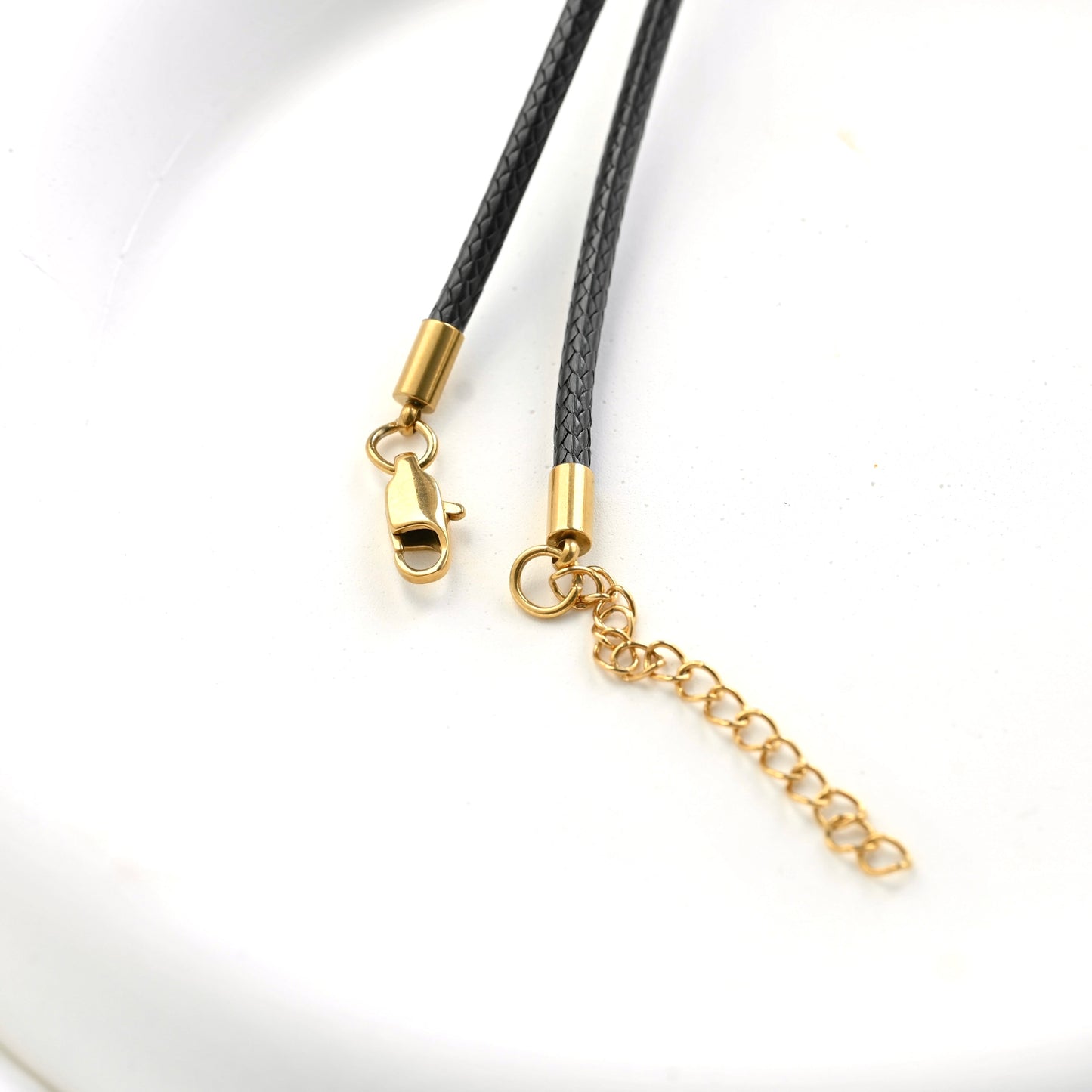 Black braided cord necklace with gold-toned lobster clasp and adjustable chain extender on a white background.
