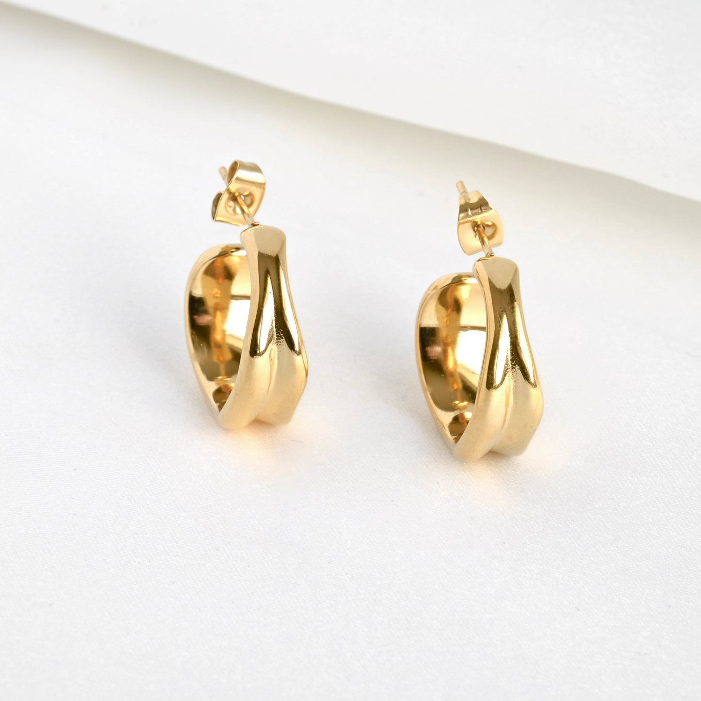 Front view of gold hoop earrings on a light gray background