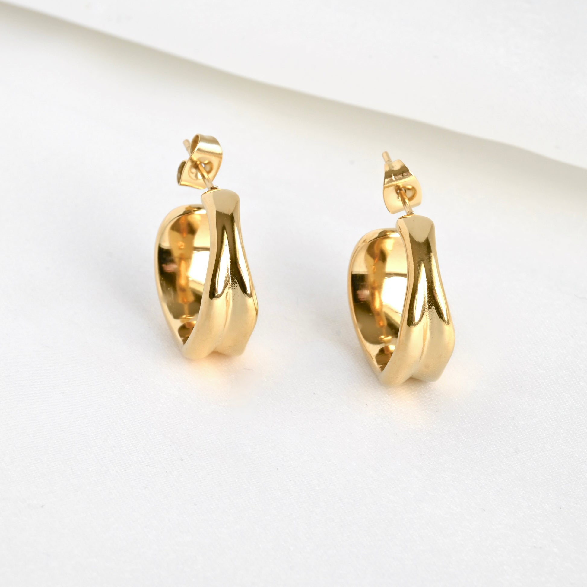 Front view of gold hoop earrings on a light gray background