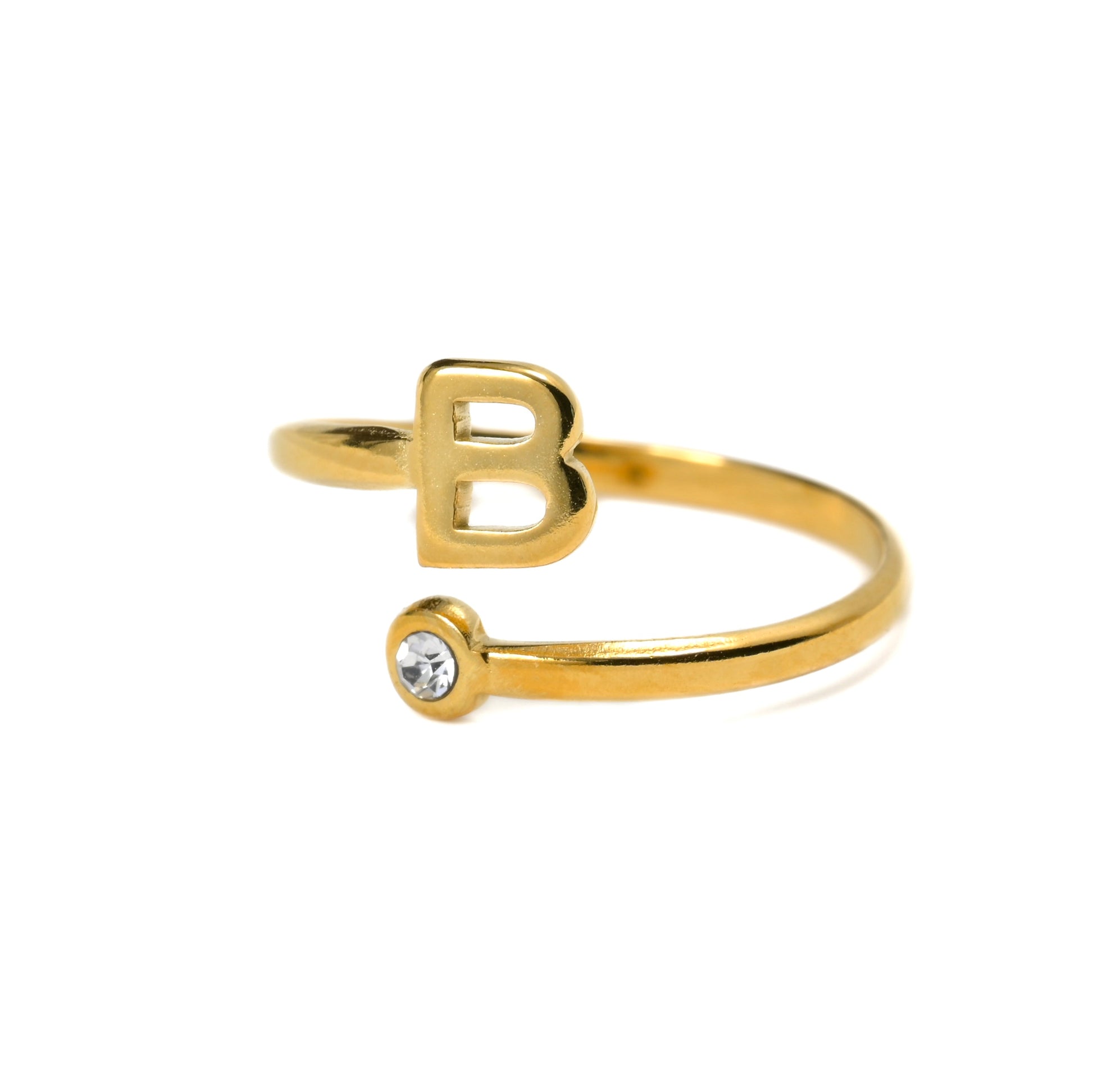 Gold ring with letter 'B' and small clear gemstone on a white background