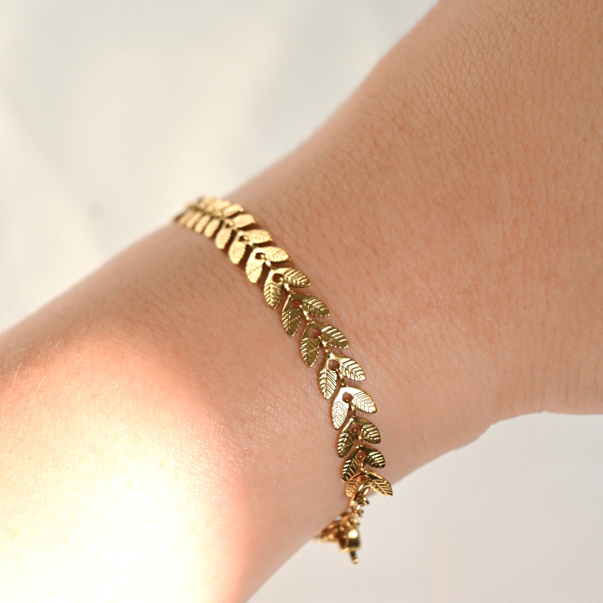Side view of gold leaf bracelet on a wrist with a blurred background