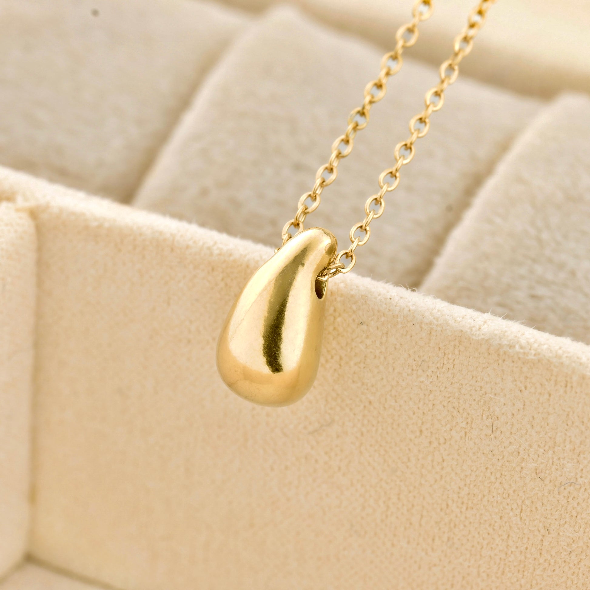 close up of  teardrop-shaped pendant on a beige textured background