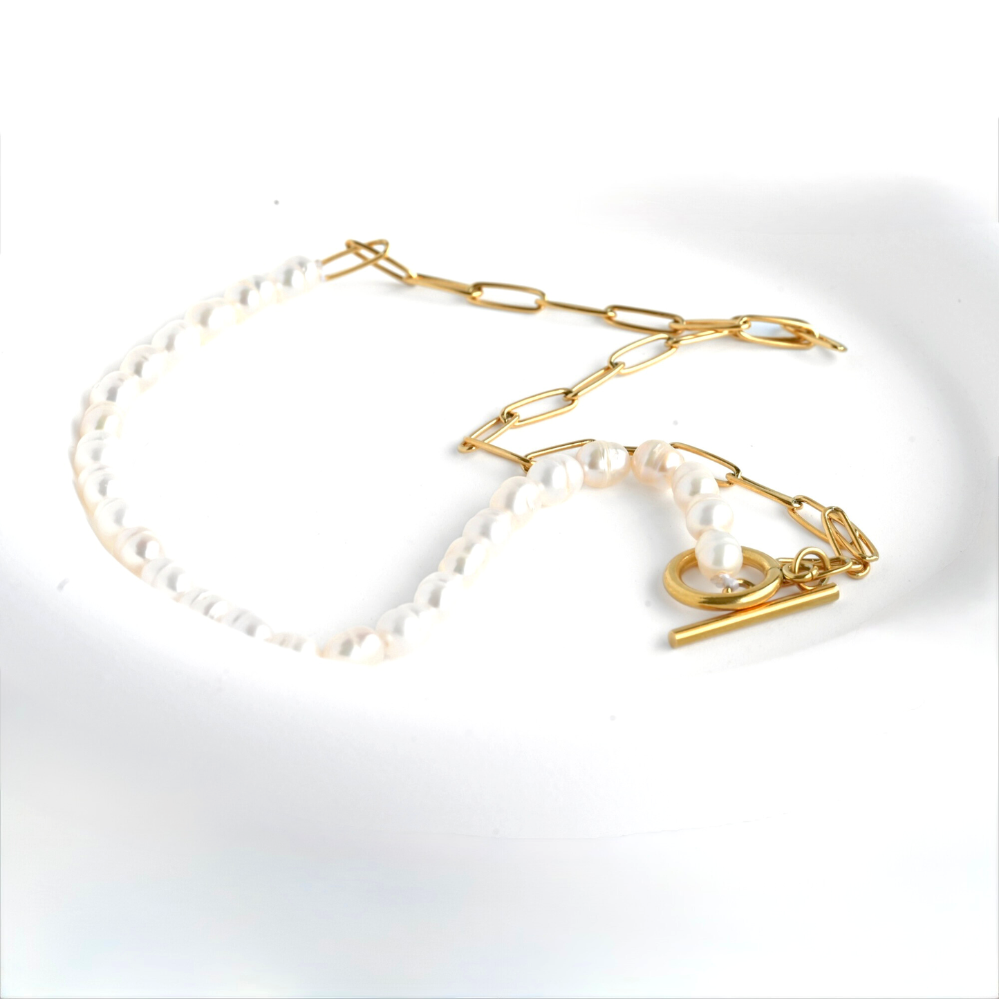 Mixed gold chain and pearl toggle necklace in a white dish