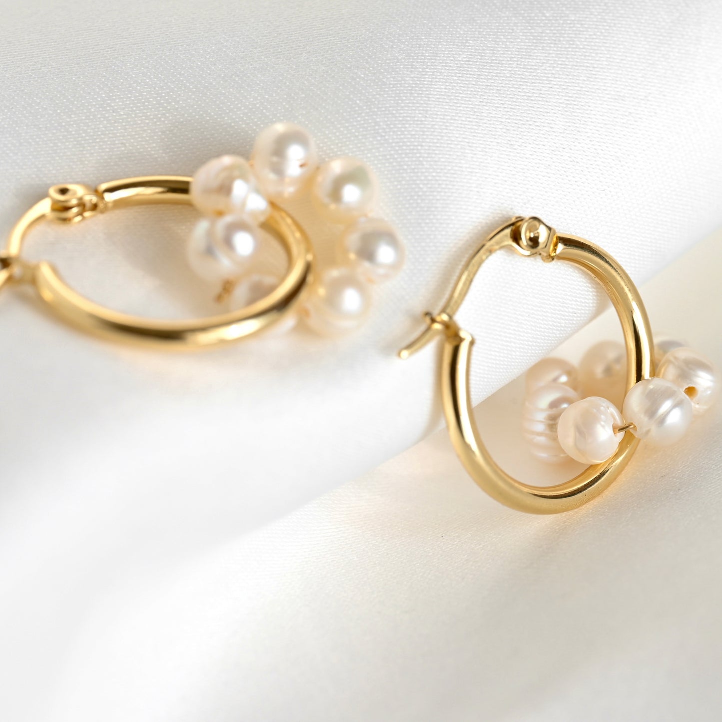 Gold hoop earrings with pearl accents on a white background
