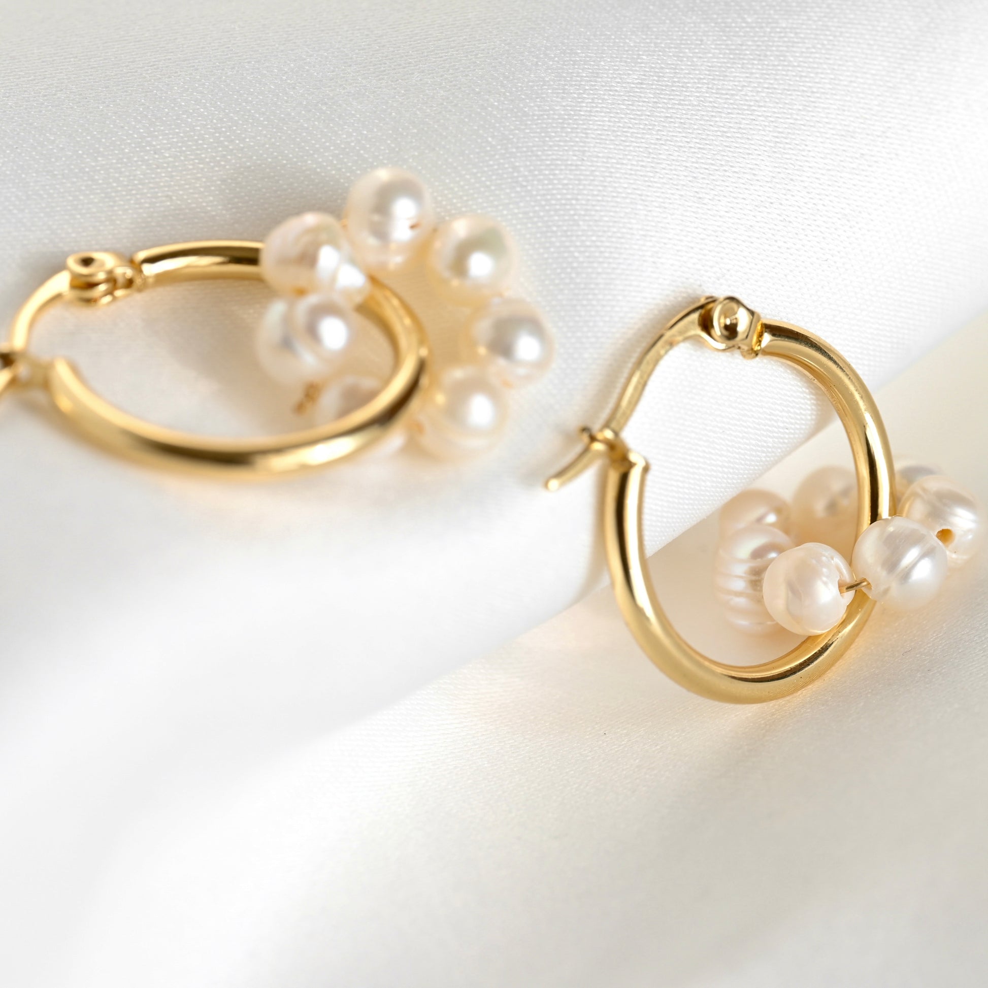 Gold hoop earrings with pearl accents on a white background