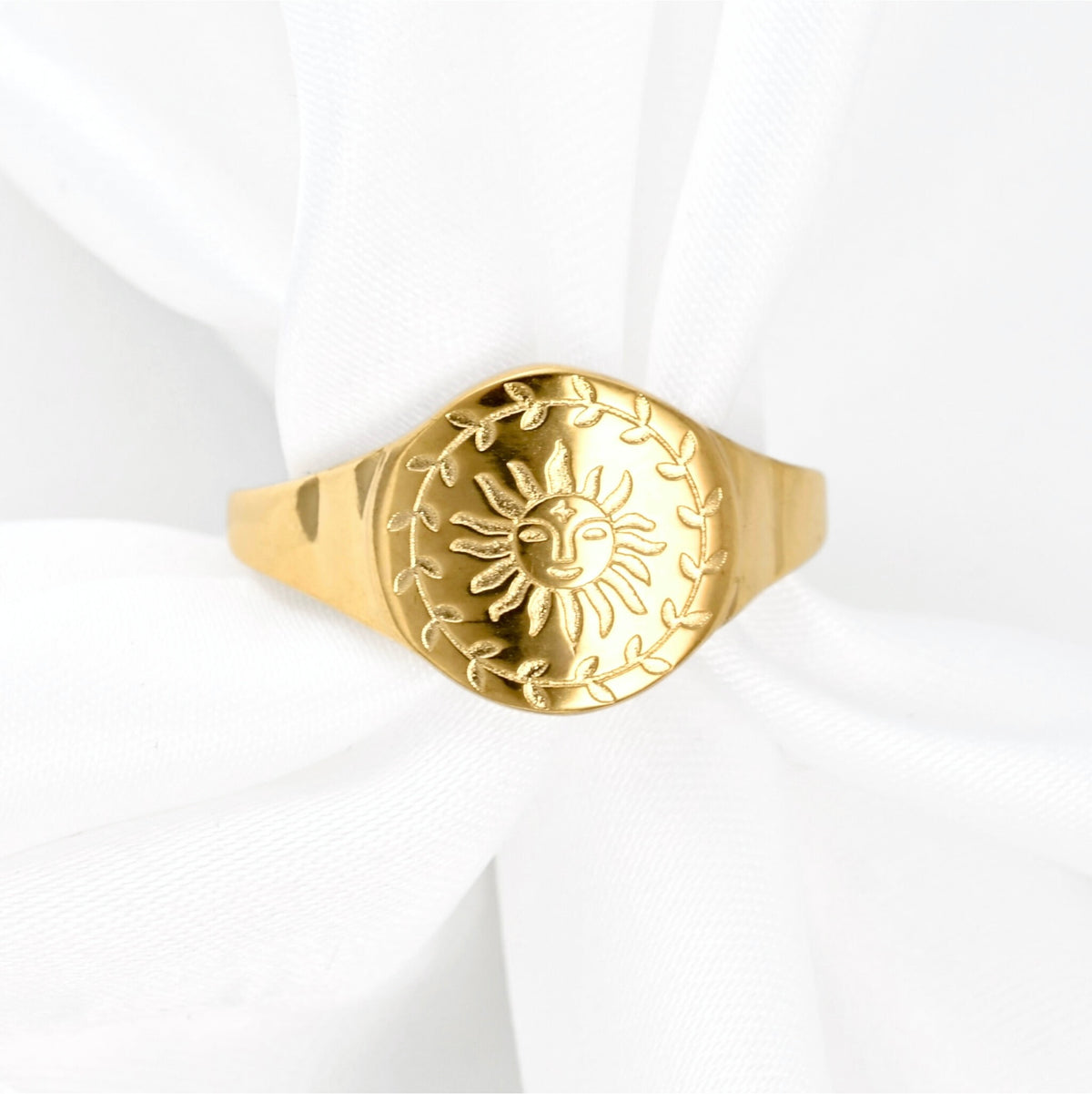 Gold ring with sun design on a white background
