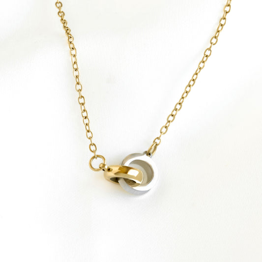 A gold chain necklace with a pendant featuring interlocking gold and silver rings, displayed on a clean white background.