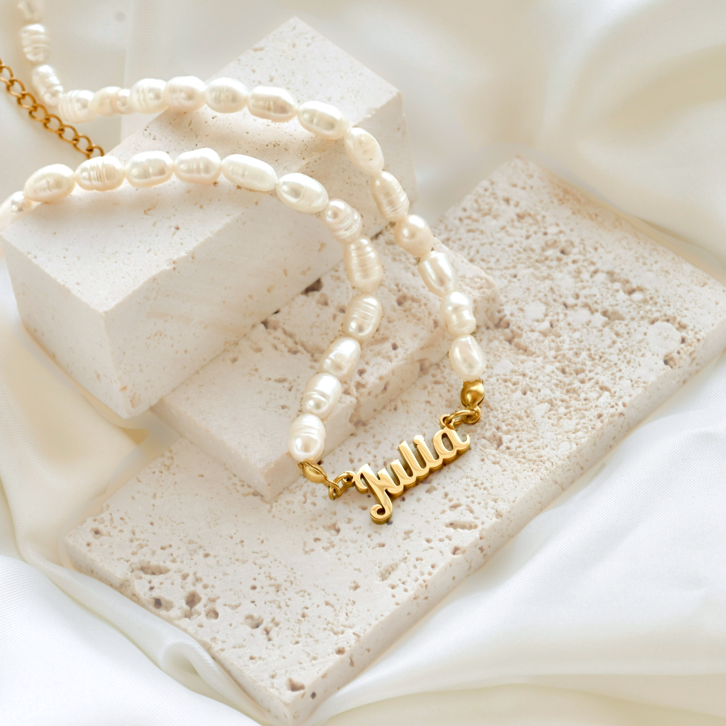 Gold 'Julia' necklace on a textured white surface