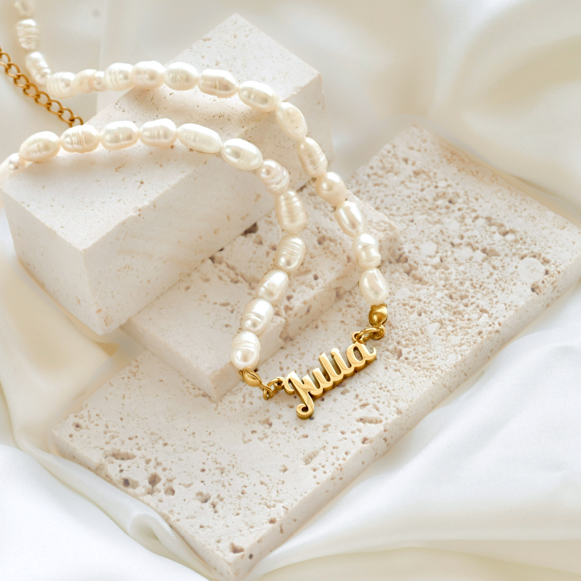 Gold 'Julia' necklace on a textured white surface