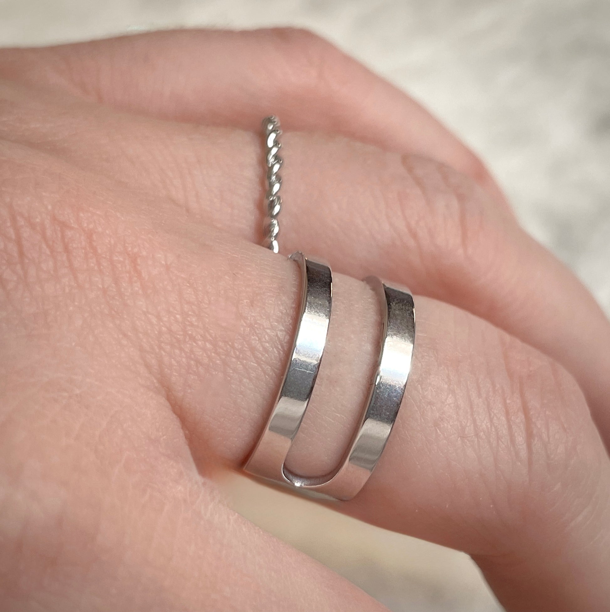 Side view of layered silver ring stacked with a dainty twisted band with a plain background