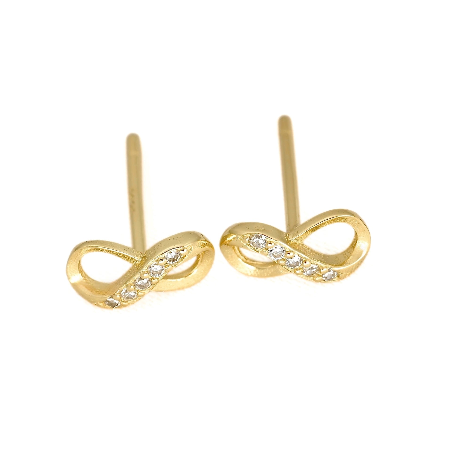 A pair of gold infinity loop stud earrings with small clear stones set along the front curve, shown on a plain white background.