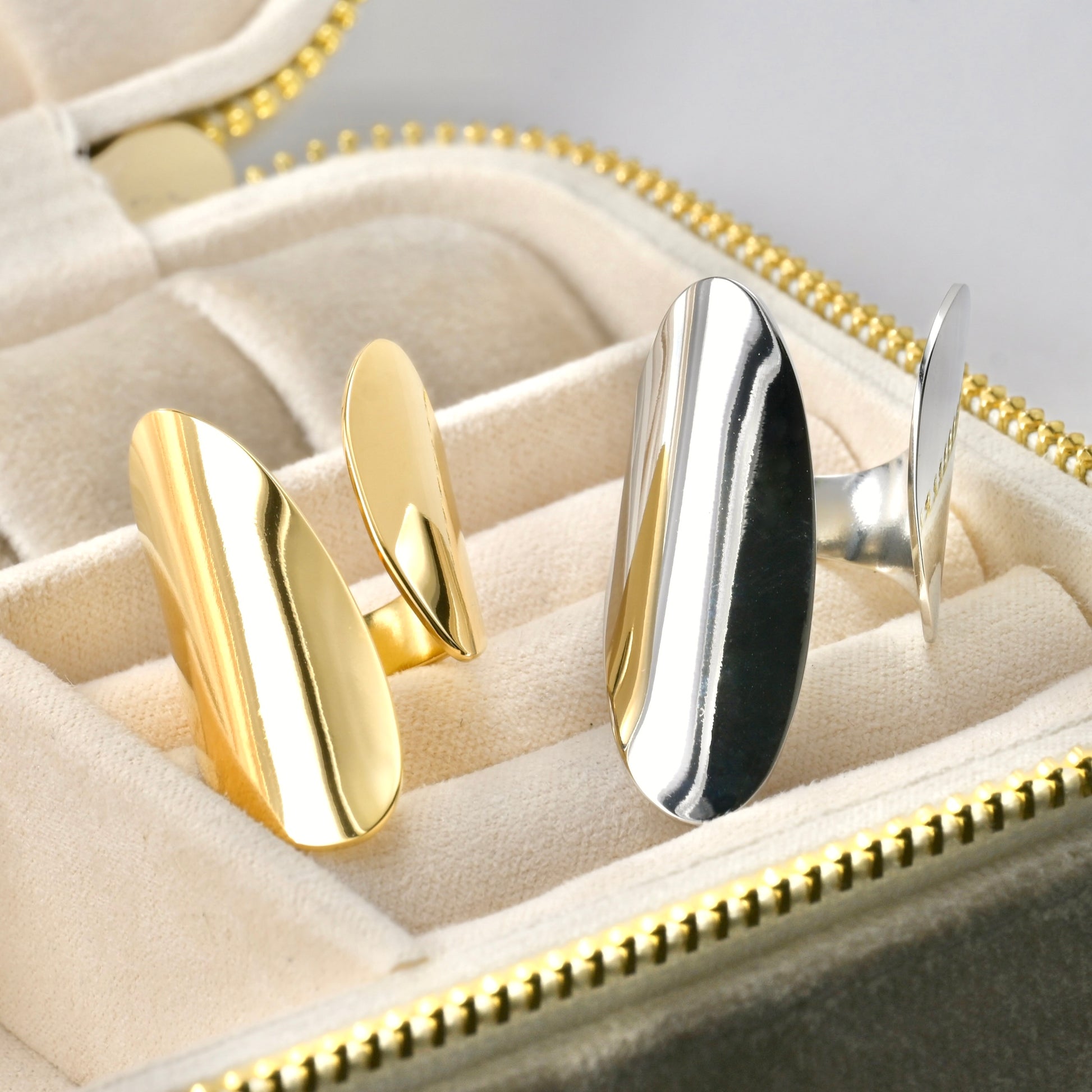 Gold and silver adjustable open rings on a jewelry case.
