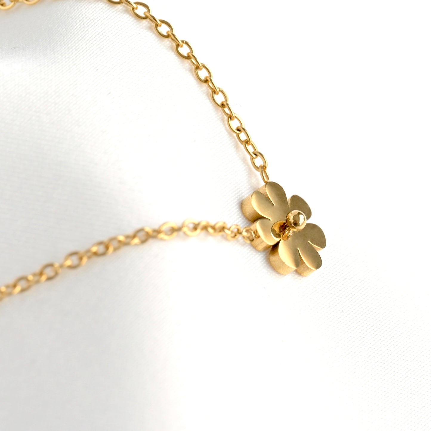 Side close-up view of gold daisy necklace on a white background