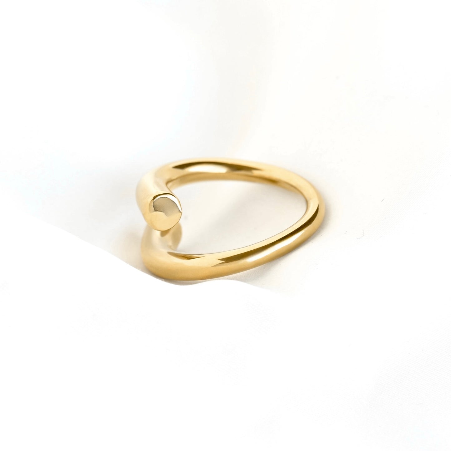 Side view of a polished gold open ring band with a small circular protruding end, photographed on a clean white background.