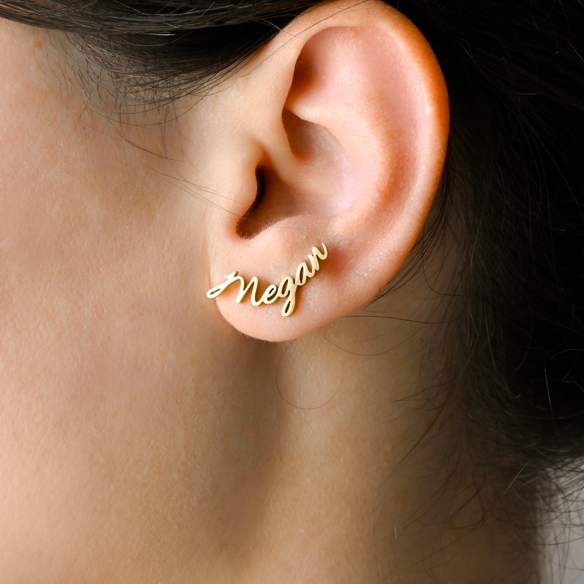 Gold climber earrings with the name 'Megan' engraving worn by a person