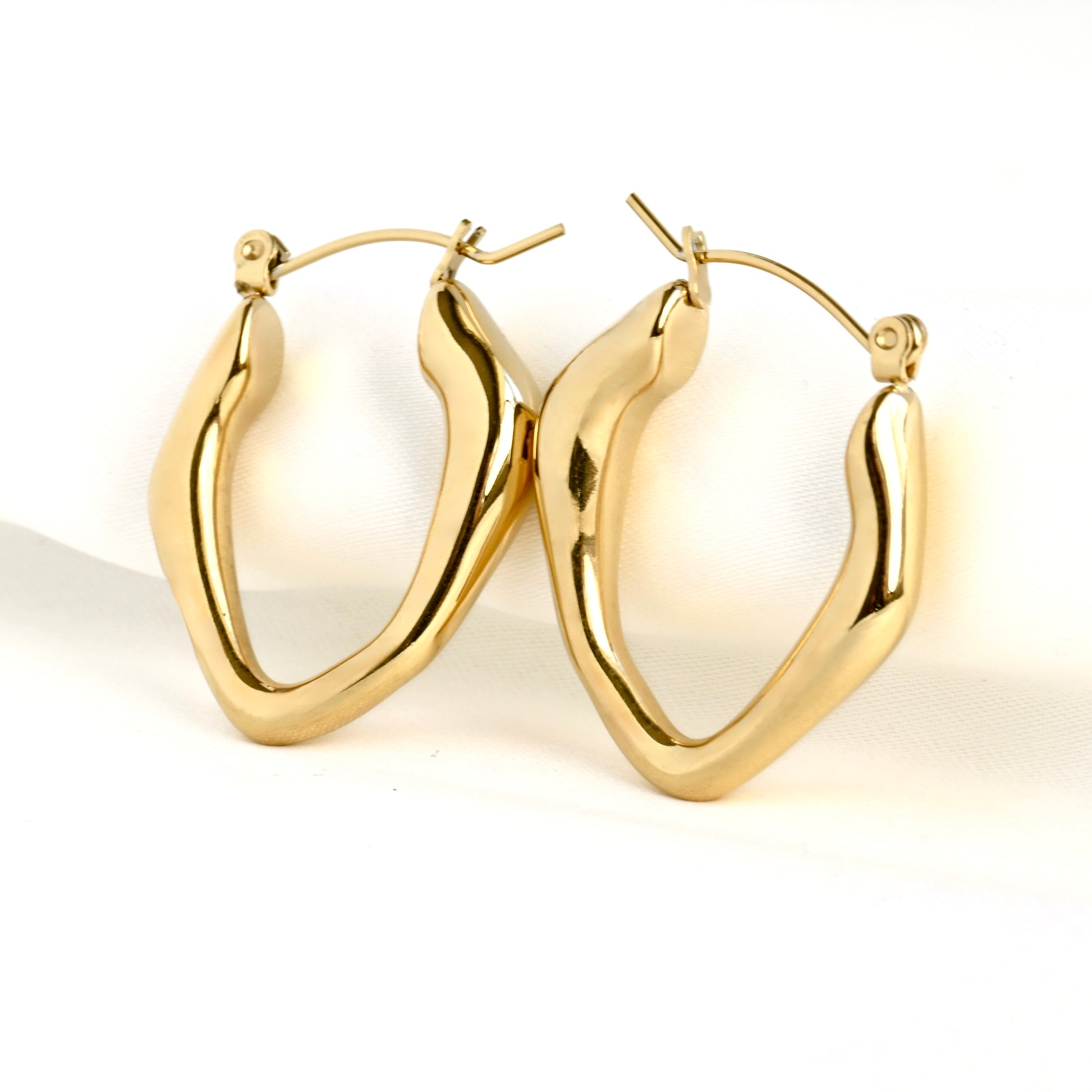 Pair of irregular shape gold hoop earrings on a white background