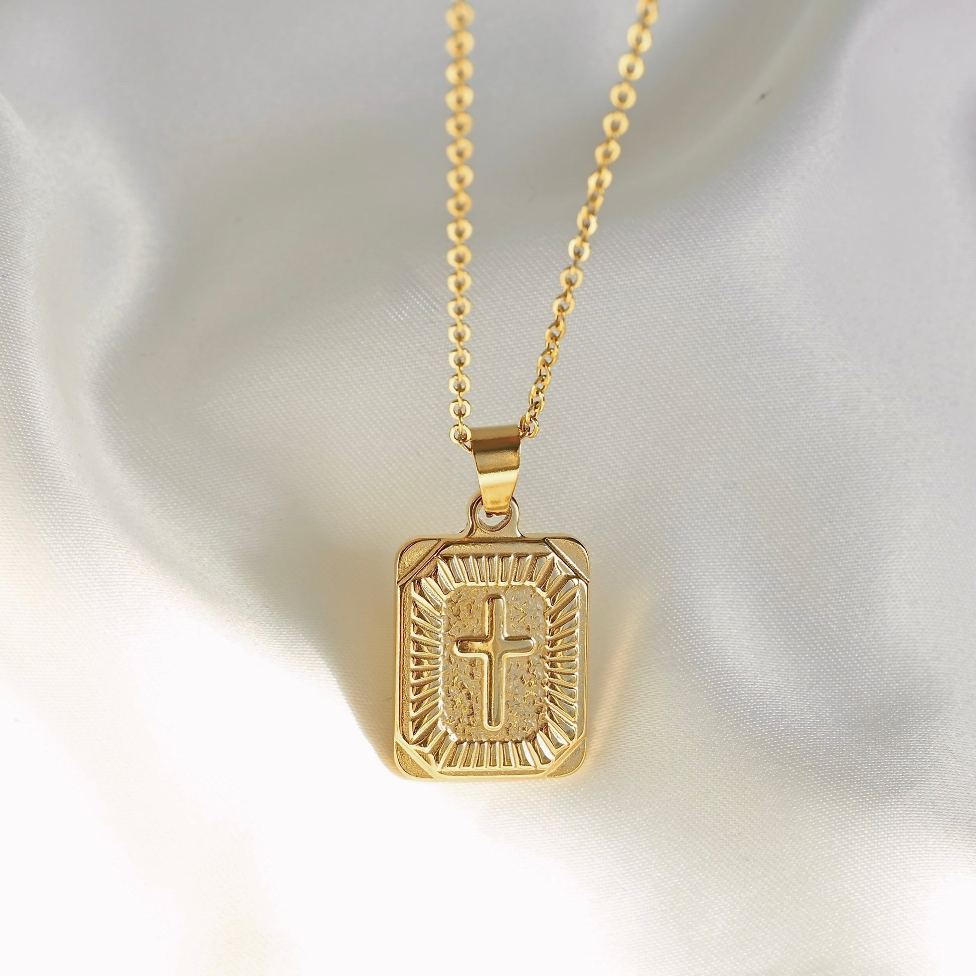 Gold pendant necklace with a cross design on a white background