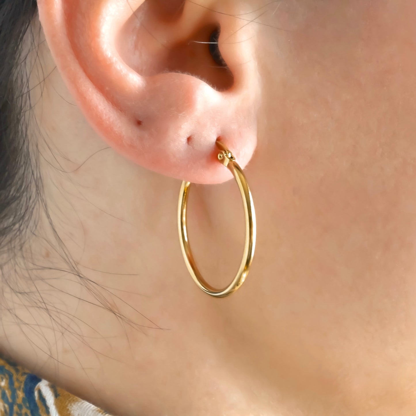 30mm medium size gold earrings worn by a person