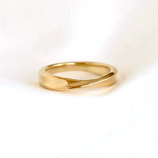 A polished yellow gold ring with a unique, slightly wavy or intertwined band design, photographed on a clean white background.
