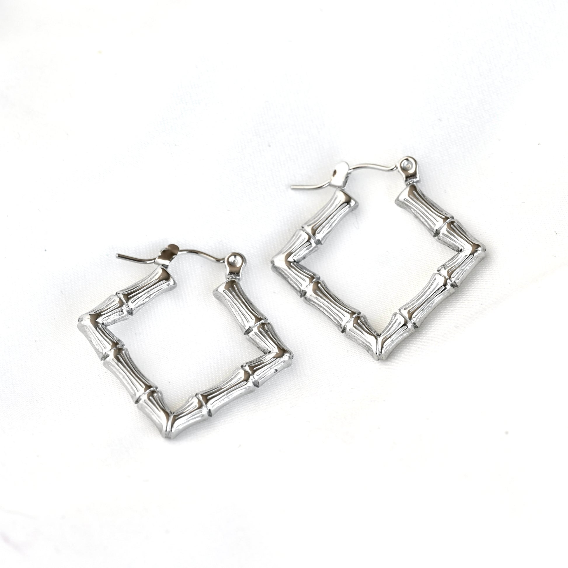 A pair of geometric silver hoop earrings designed to look like segmented bamboo stalks, shown on a plain white background.