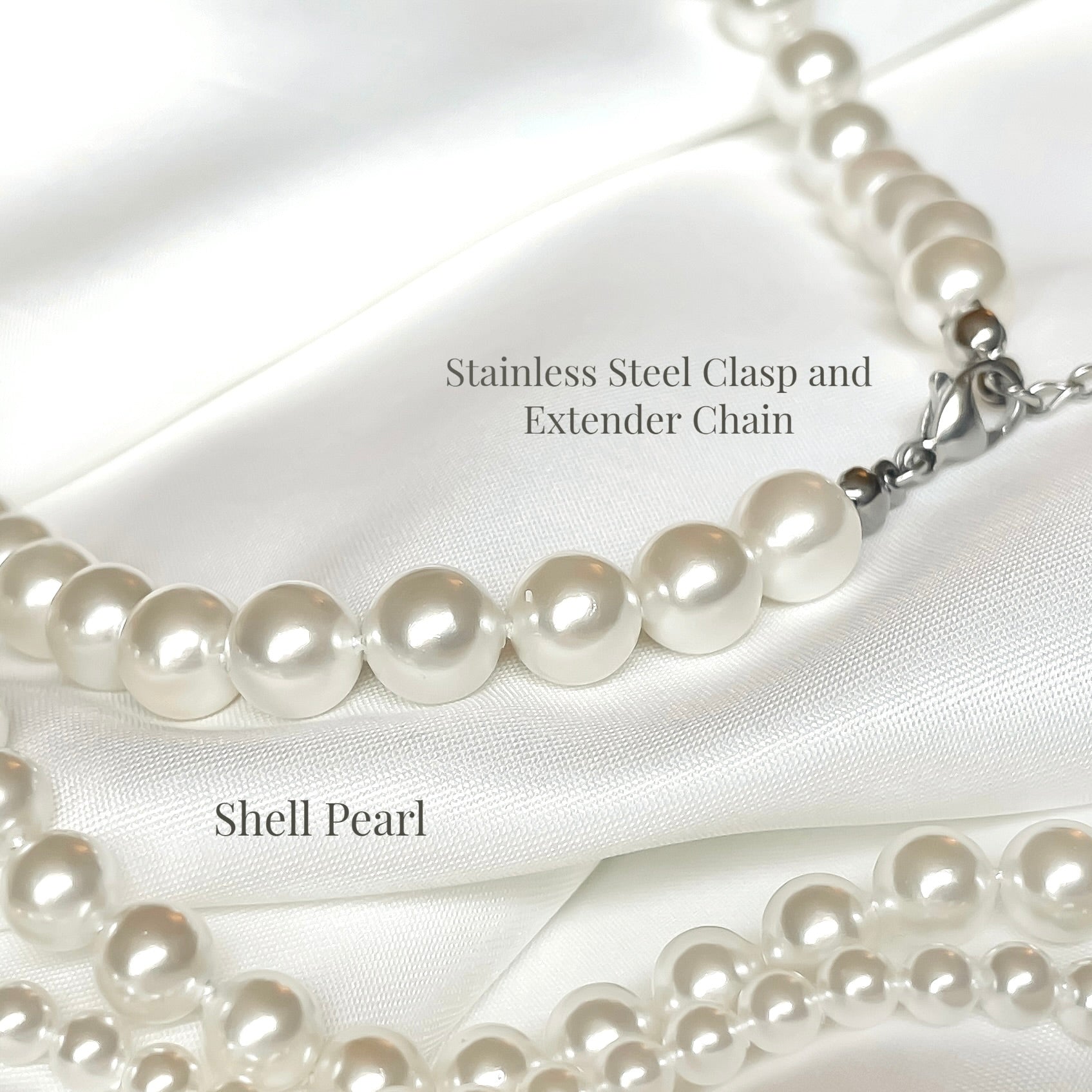 Shell pearl necklace with silver stainless steel clasp on a white satin background