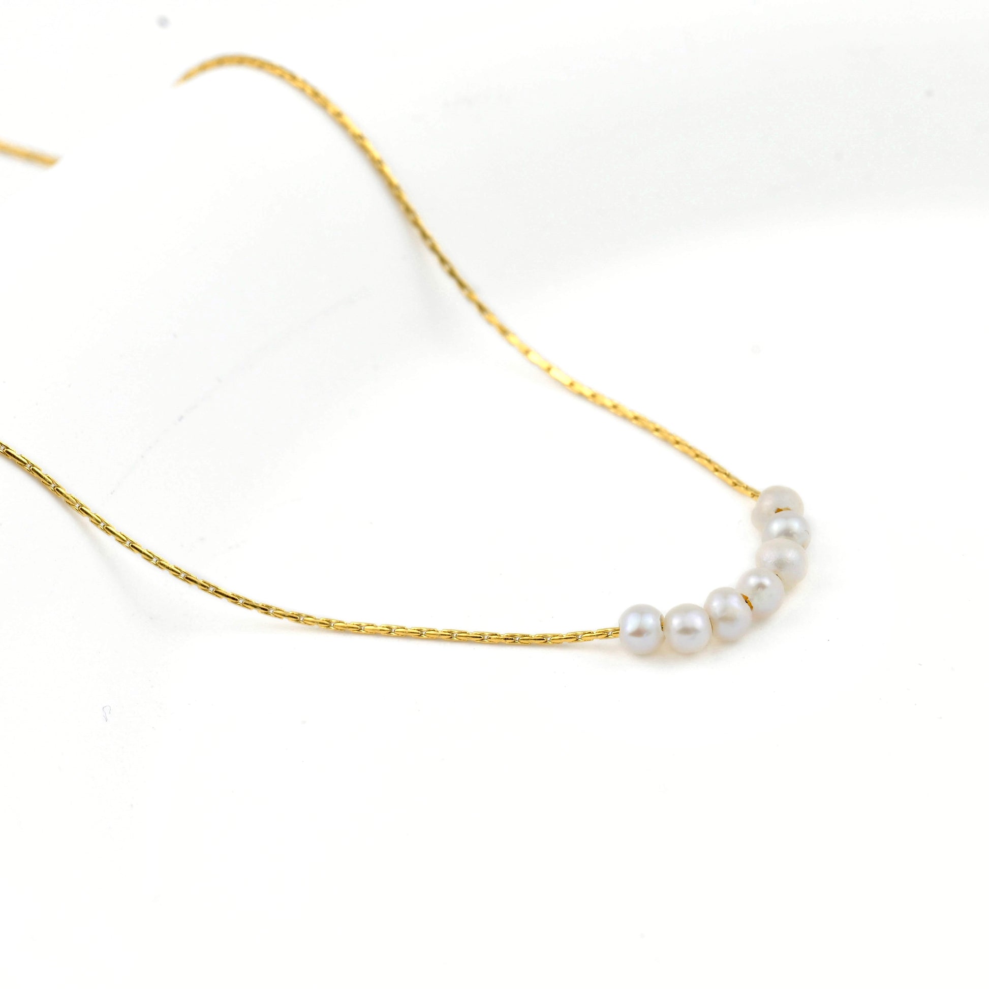 Gold necklace with pearls on a white background