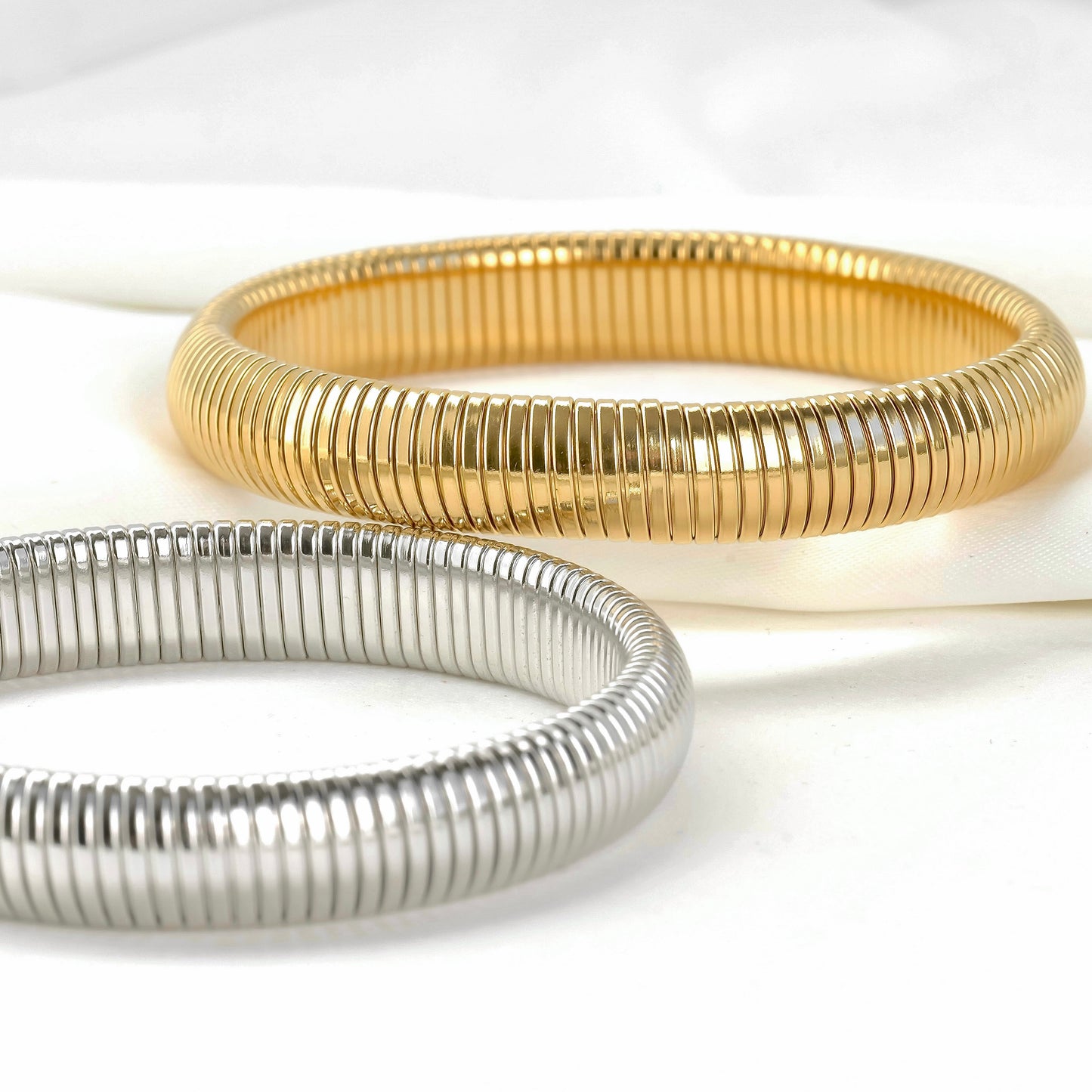 Two gold and silver bangles on a white background