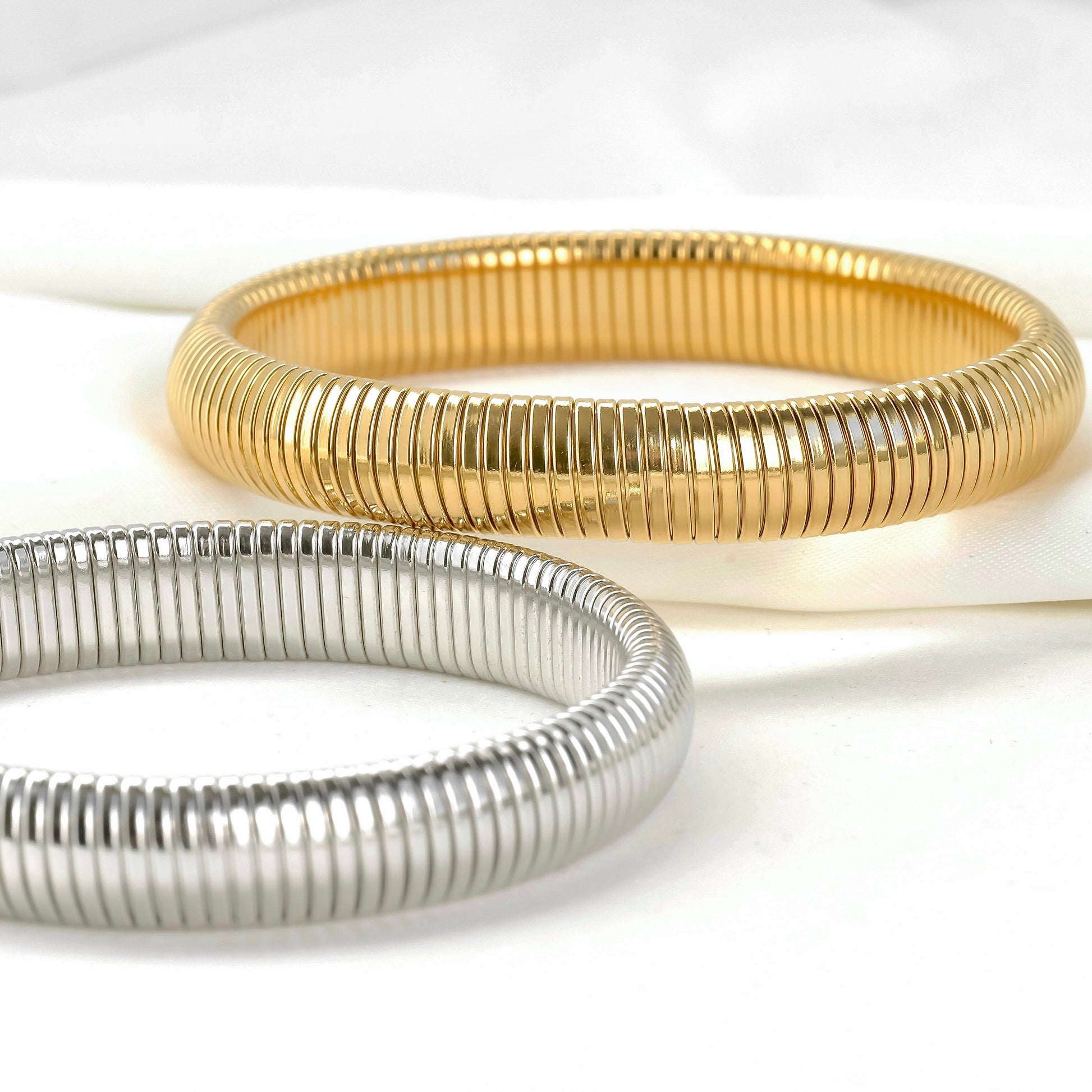 Two gold and silver bangles on a white background