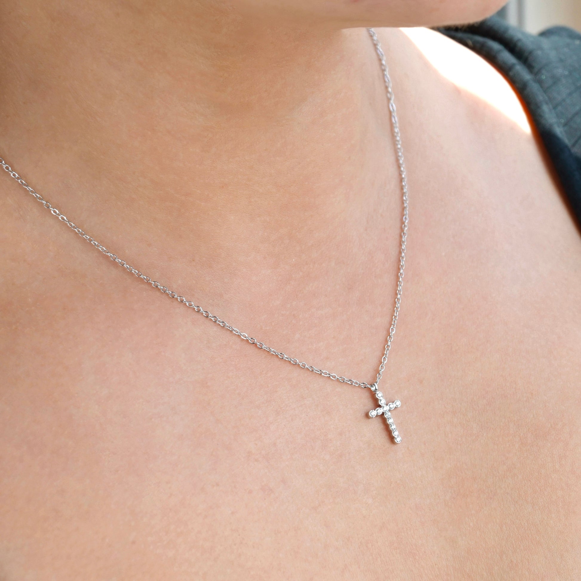 Side view of silver cross necklace on a person's neck