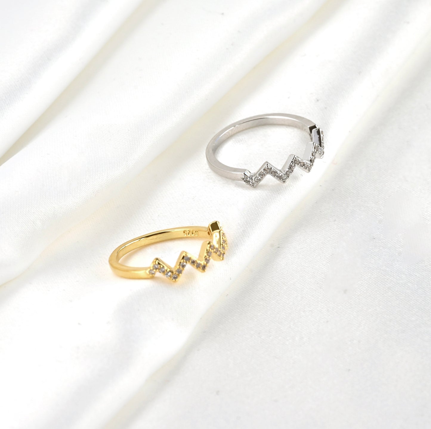 Two rings, one gold and one silver, with S925 stamp on a light background