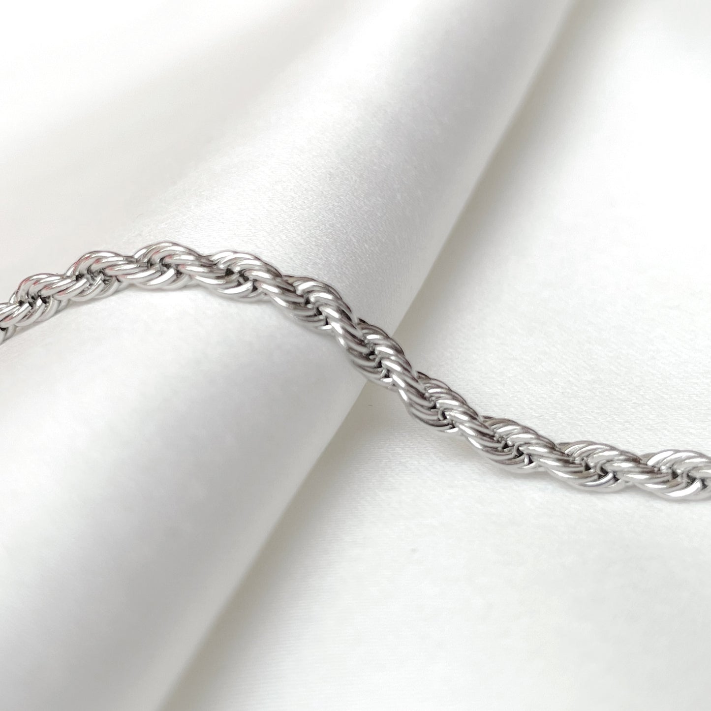 2mm silver rope chain on a white fabric background