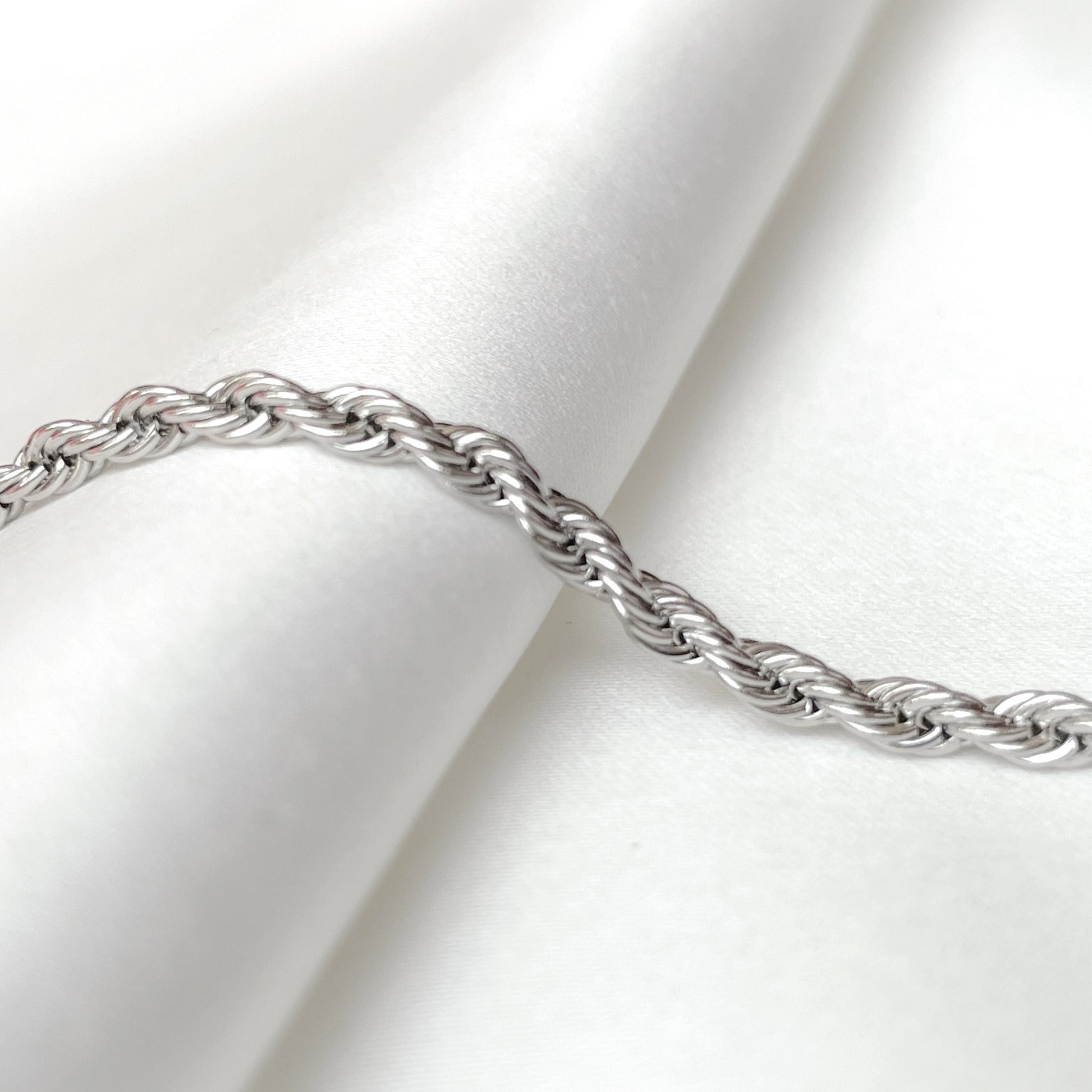 2mm silver rope chain on a white fabric background