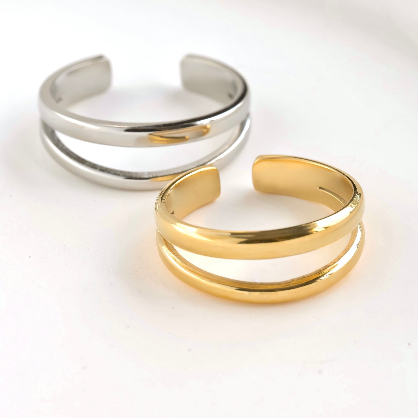Front angled view of Two gold and silver open rings on a white background