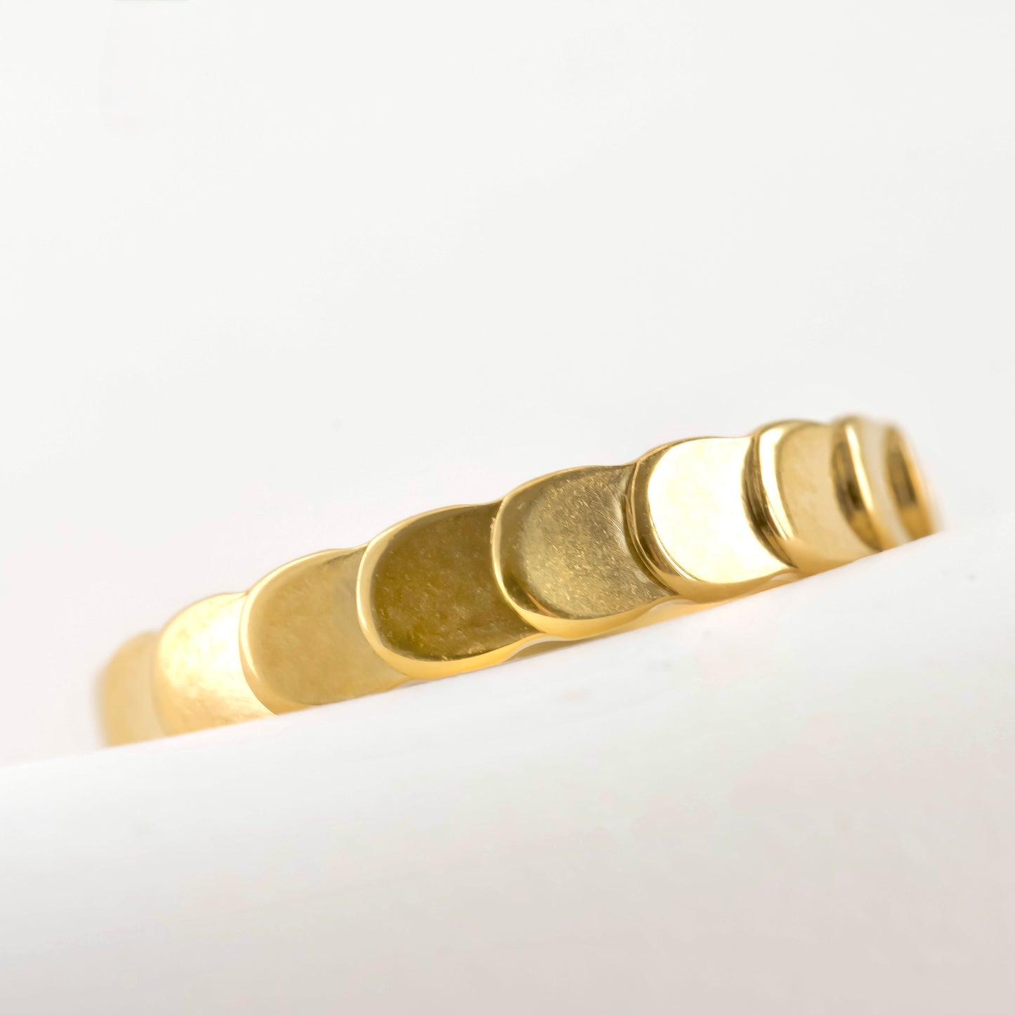 Scalopped Gold ring with a minimalist design on a light gray background