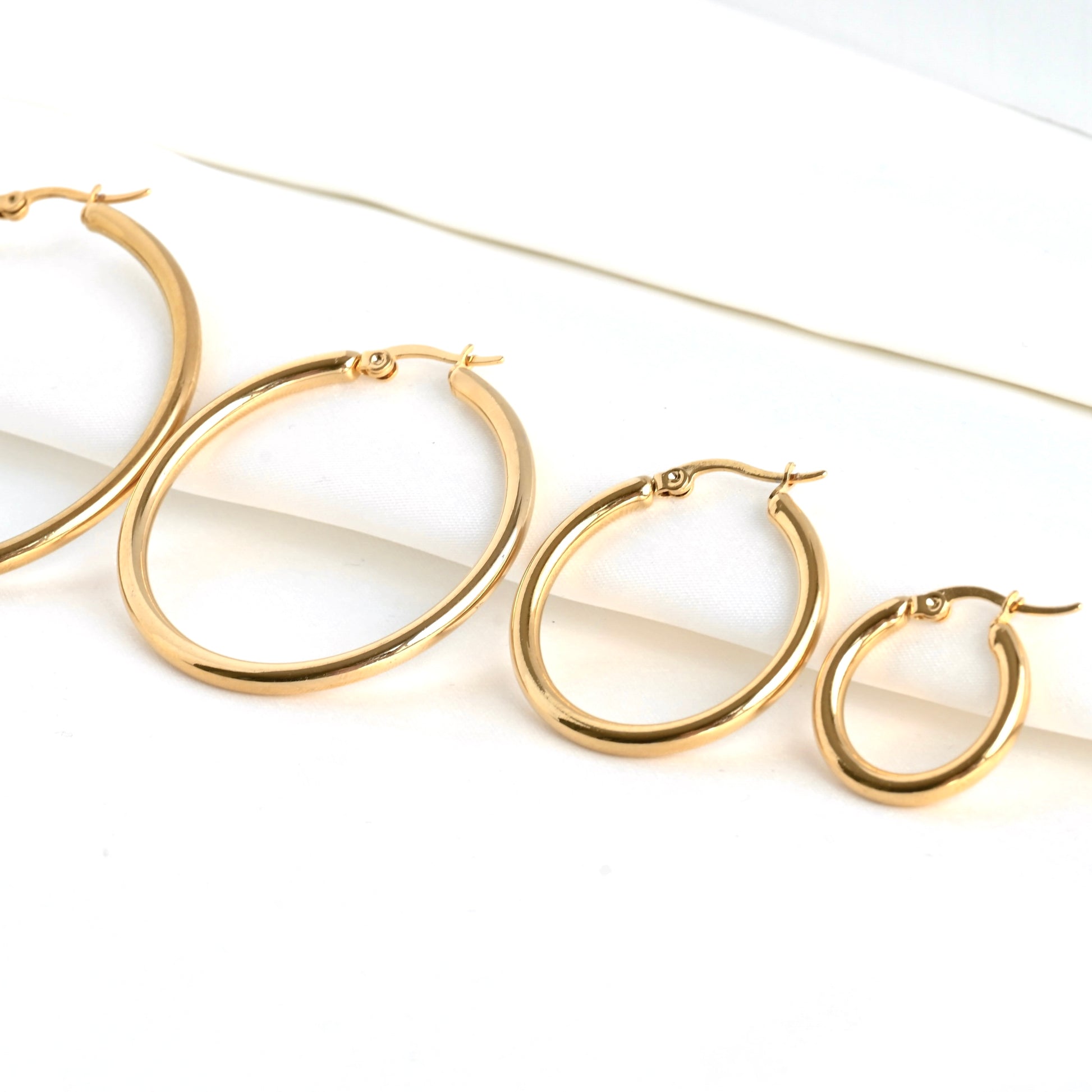 Gold hoop earrings of 4 different sizes from 20mm to 50mm side by side on a white background