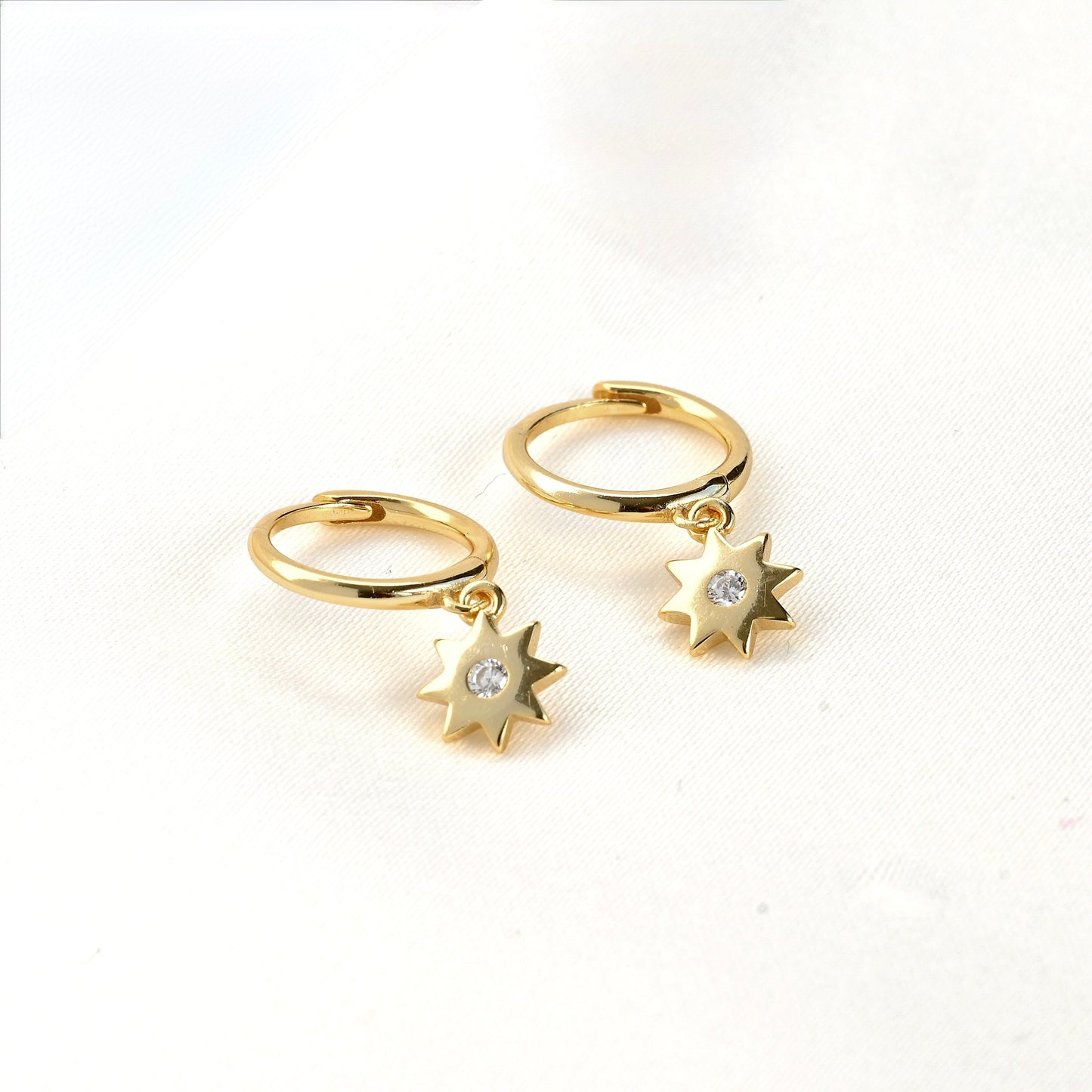 Gold hoop earrings with star charms on a white background