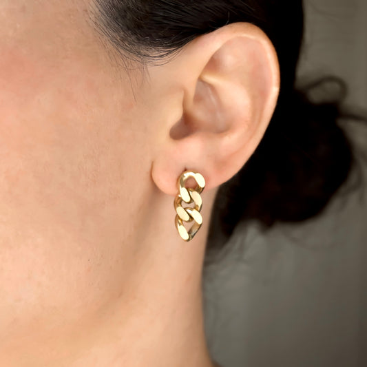 Gold cuban chain earring worn by a person with a neutral background