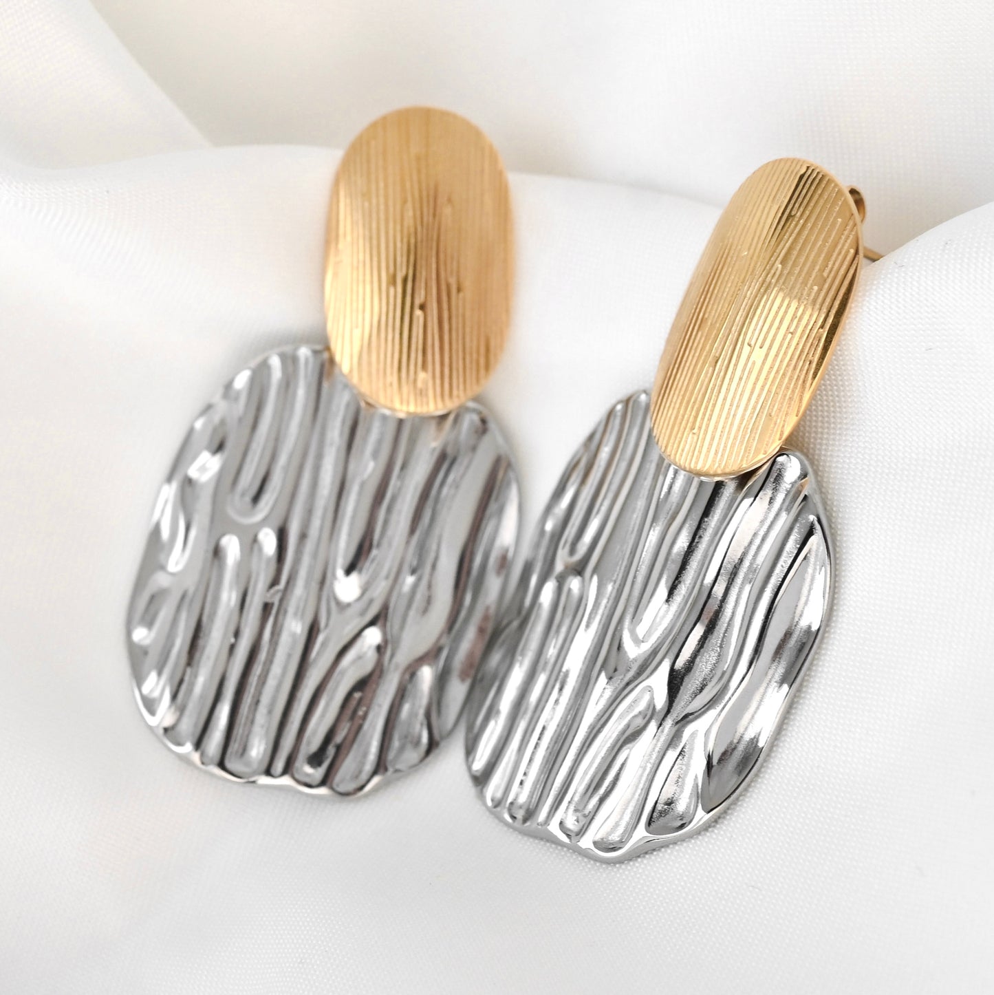 Pair of earrings with gold and silver designs on a white background