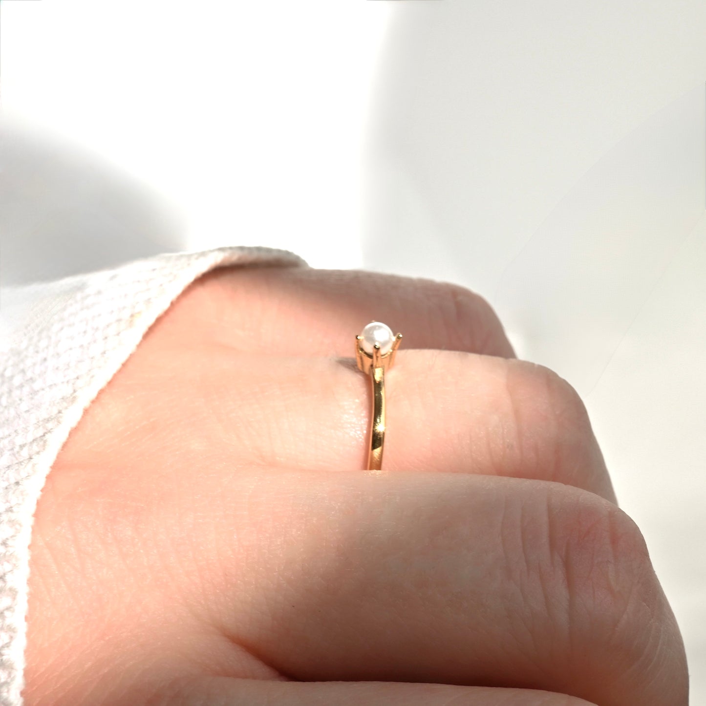 Side view of pearl ring on a person's finger  under direct sunlight