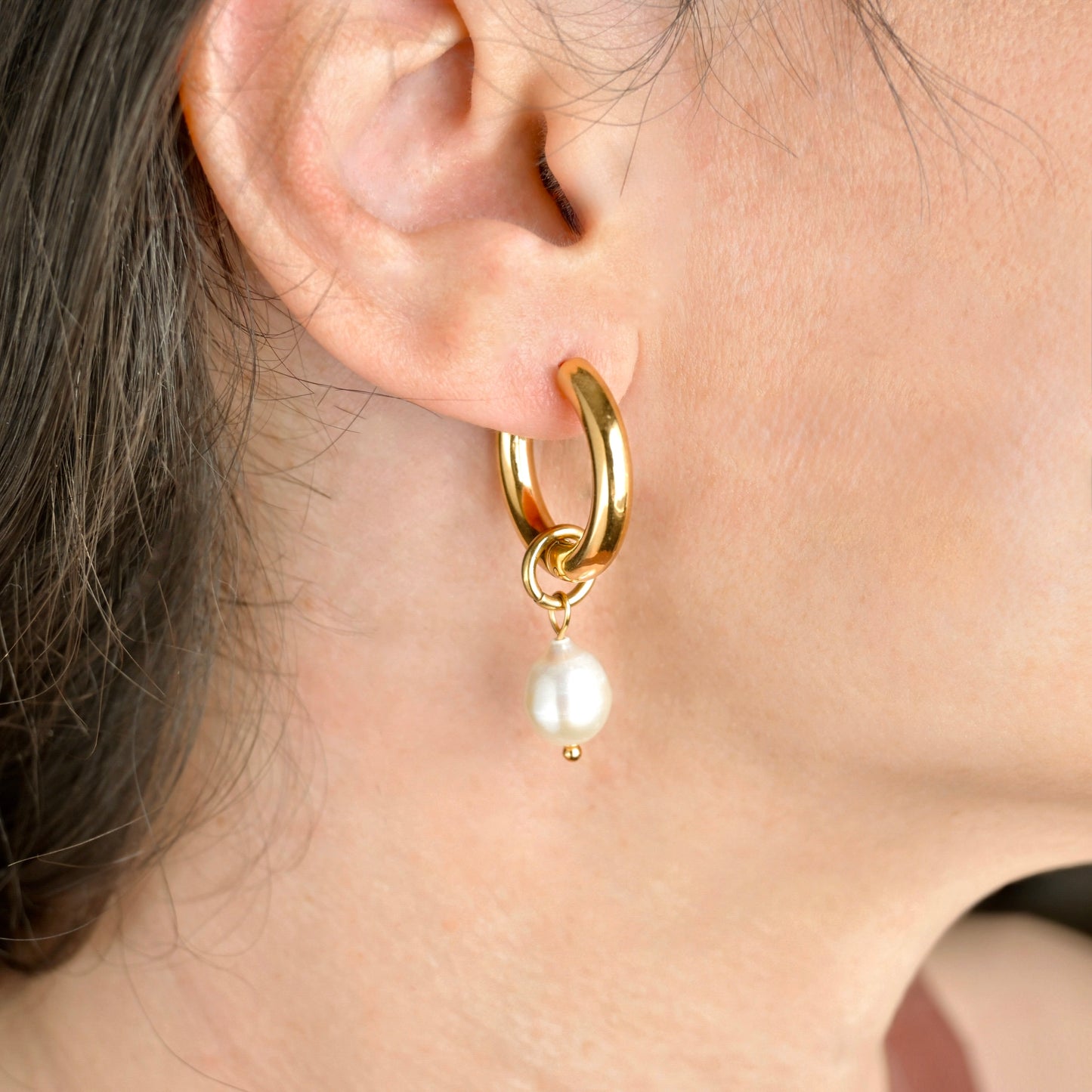24mm thick gold hoop earring with a pearl drop worn by a person